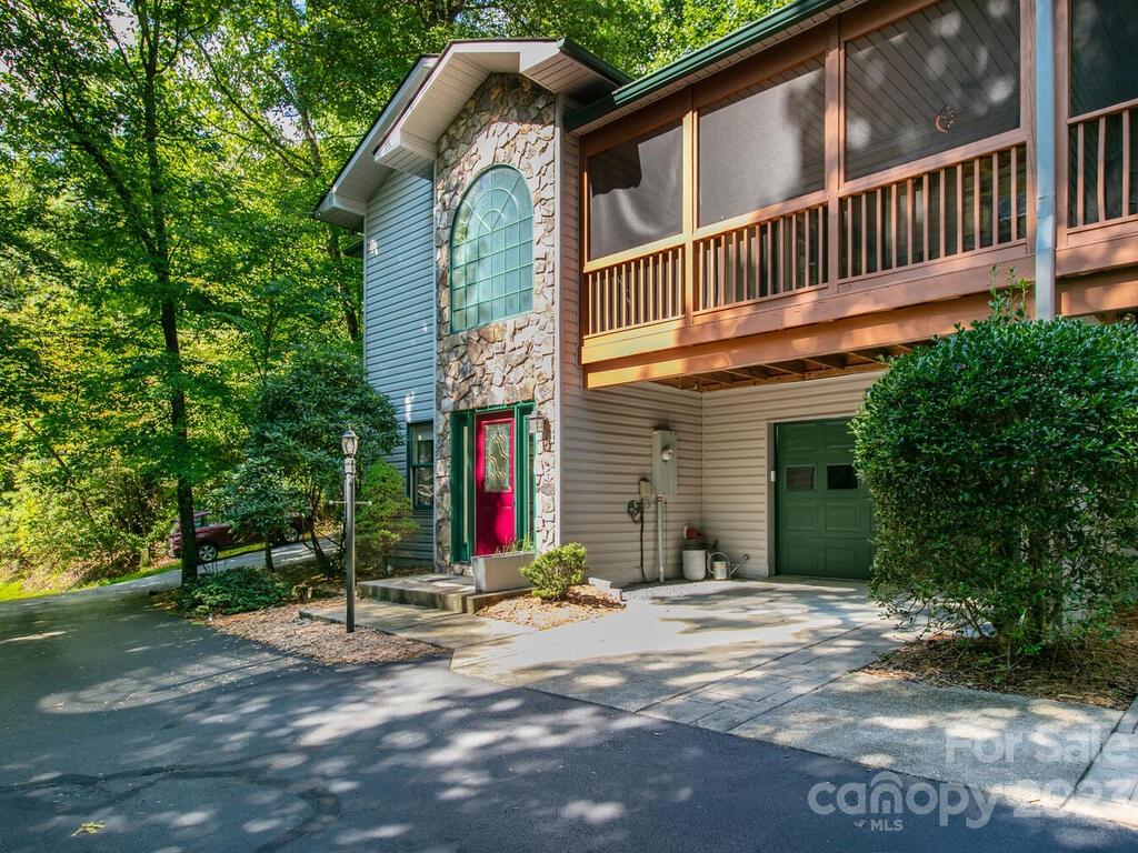 Spectacular, well-kept townhome in Qualla Village within the coveted natural setting of Connestee Falls! The main floor touts a remarkable open floor plan with vaulted ceiling, built-ins, skylights, magnificent stone-framed gas logs fireplace, and access to a dreamy screened-in front porch. Spacious primary bedroom suite on main includes walk-in closet and private bath. The finished basement area offers 2 guest bedrooms and full bath. Attached garage has shelving in place. Enjoy the surrounding forest while relaxing on the large back deck! Highlights include newer water heater, overflow parking, low maintenance, and gated community. Community amenities include hiking trails, golf, clubhouse, tennis, lakes, waterfalls, outdoor pool, picnic area, playground, recreation area, fitness center, and more. Qualla Village in Connestee Falls offers a lifestyle of ease and enjoyment in beautiful Brevard!