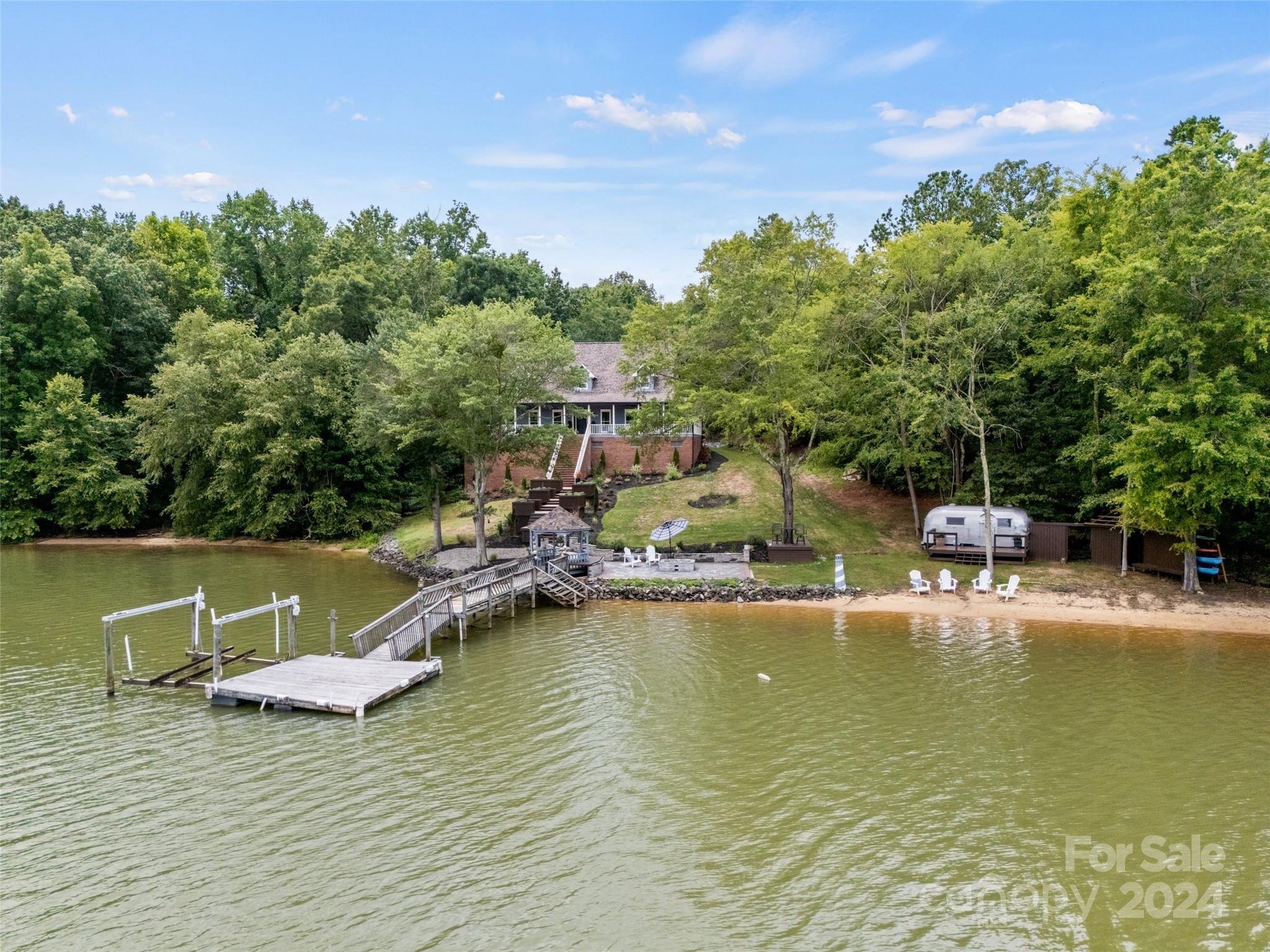 **Attention: Price improvement of $330k below appraisal** Waterfront meets modern luxury! Welcome to this elegantly renovated home featuring high-end finishes & amenities, seamlessly blending comfort of lakeside living w/modern style on private 2.6 acre lot. Outdoor spaces are an entertainer’s dream from expansive wrap-around porch to waterfront beach paver patio. Access to your lake adventures is seamless w/the floating dock & boat lift. Enjoy the warmth & charm of the great rm with its vaulted ceiling & wood-burning river rock frpl. A quartz waterfall island, custom cabinets, Thermador refrigerator, gas stove & designer lighting create a stunning kitchen. Spacious primary suite features a custom closet, heated Italian marble & a free-standing Jacuzzi tub.Plus a second living quarters w/ private basement residence, could be inlaw suite. Every feature of this home is designed for comfort, style & functionality, making it a true sanctuary. Seller giving a $40K credit for the dock repair