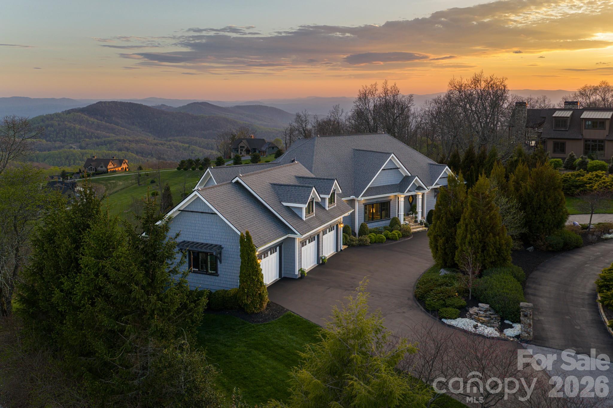 Unforgettable panoramic views and elegant mountain aesthetic define this beautiful ridgetop residence within the gated community of Grand Highlands at Bearwallow Mountain. At nearly 4,000 feet of elevation, the Blue Ridge Mountains are not a backdrop — they are a part of your everyday experience. Wake up to the beautiful sounds and sights of the mountains, and end your day watching the brilliant colors and layered dimension of sunset with long-range south-facing views from your back deck.

Designed to flow and live effortlessly, the light-filled, 3,313 sq ft floor plan offers thoughtful design and stunning outdoor living spaces. Gorgeous principal rooms with large windows carry the views throughout, while three fireplaces anchor multiple living spaces with a romantic and elevated mountain aesthetic. The designer kitchen and dining area are inviting with refined elegance: custom cabinetry with integrated refrigerator, a high-end range, marble tile backsplash, and a multi-functional island with integrated sink and counter-height seating, equally at home for a quiet breakfast or an evening with friends. And when the golden hour glow begins to arrive, simply open the doors and step onto the deck — wine in hand, fire table glowing, guests gathered as the sun dips behind the ridgeline.

Step outside and you'll find a backyard of lush, thoughtfully designed landscaping and outdoor living spaces. Enjoy a private hot tub with the perfect vantage point to enjoy long range views. A fire pit seating area nestled among the landscape invites evenings spent in the open air, surrounded by the mountains. A circular driveway, three-car garage, and fenced yard complete the story, creating a welcoming, warm and truly elegant home that lives as beautifully as it looks.

Community life at Grand Highlands is as rich as the scenery. A beautifully appointed lodge-style clubhouse serves as the heart of the neighborhood, offering a fitness center, event and meeting spaces, a library, a community garden, and a lively social calendar filled with pub nights, trivia, concerts, and more. Outside, residents enjoy a dog park, tennis and pickleball courts, and peaceful hiking trails — plus direct access to two trailheads. Just 25–30 minutes to both Asheville and Hendersonville, close to all the culture, cuisine, and conveniences each city offers.