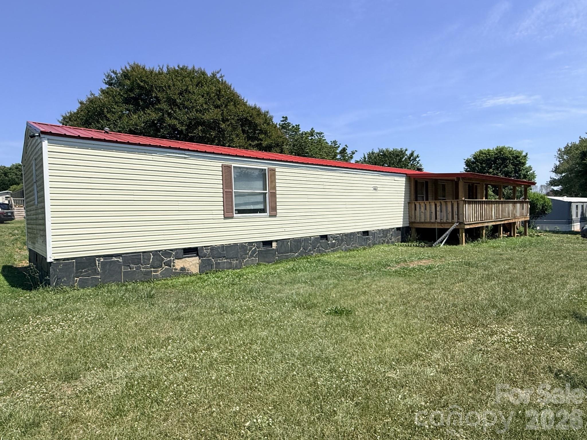 Two-bedroom, two-bath manufactured home built in 2000, offering approximately 1,120 heated square feet on a 0.38-acre corner lot. This property is sold as-is.

The front approach includes steps to a covered front porch. The front door opens into the main living area with the kitchen directly accessible to the left. The kitchen features an open layout connecting to the living space, with the laundry area positioned adjacent to the kitchen. The two bedrooms are separated by the central living space. The primary bedroom is located on the left side of the home and includes an attached bathroom with a bathtub. The secondary bedroom is positioned on the opposite side. A second full bathroom is accessible from the main living area.

The covered front porch provides outdoor seating. The back deck extends the living space outdoors and overlooks the backyard where the fruit trees are established. The storage shed provides space for tools, equipment, or seasonal storage.

It also features established fruit trees planted approximately five years ago.