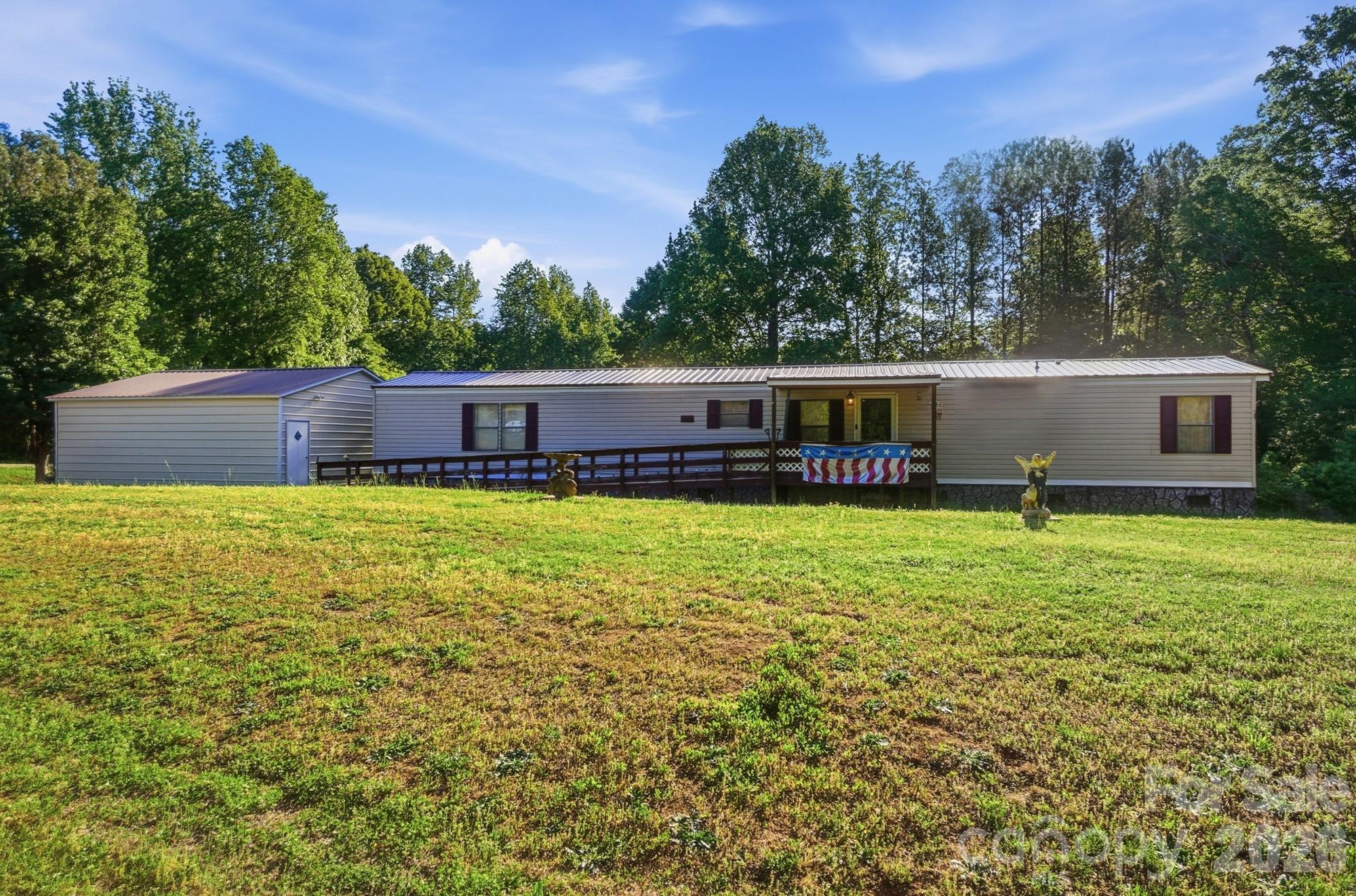 Well-kept and much-loved, this customized 16x80 single-wide home offers comfortable living, generous space, and the acreage so many buyers are looking for. Thoughtfully expanded with two room additions, the home now features added dining room space plus a flexible bonus area off the family room—perfect for a sitting room, office, hobby space, or additional gathering area. The split-bedroom floor plan provides privacy, and both bedrooms are nicely sized, including a spacious primary suite with a large primary bathroom.
Enjoy outdoor living from the covered front deck or relax year-round in the enclosed back sunroom. The roof is covered with the front half metal and the back half regular roofing shingles. A newer metal building, installed only a few years ago, includes two automatic garage doors with room for two vehicles plus additional storage or workspace. With large acreage, useful outdoor space, and convenient access to York and surrounding areas, this property offers a wonderful opportunity for someone looking for a forever home with room to spread out.