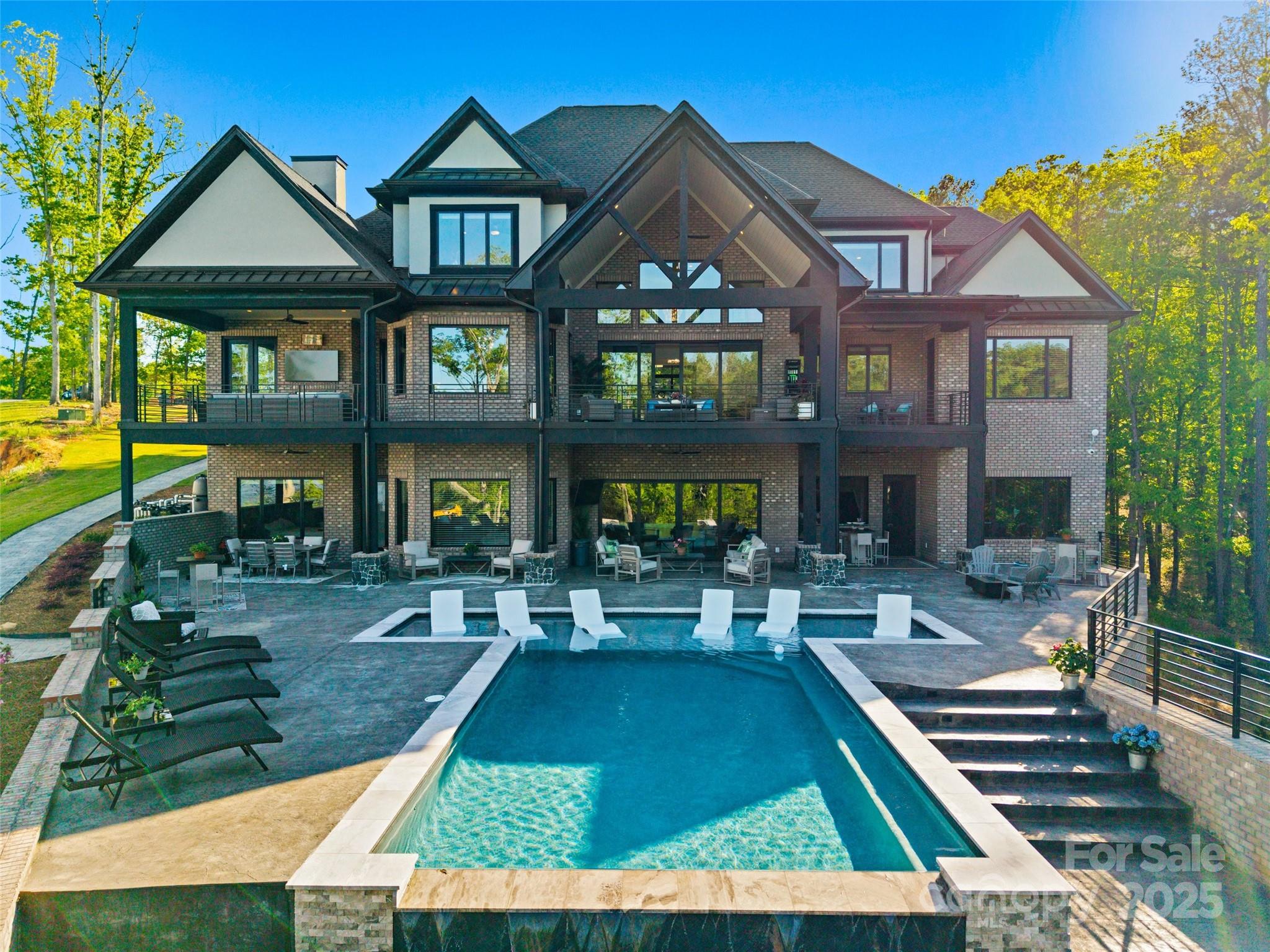 You do not want to miss this one-of-a-kind waterfront, 8000 sq ft. treasure on Lake Wylie! Built in 2024, enjoy effortless lake living, this home sits on 1.86 acres, and located in a quiet cove with main channel views. Wake up every morning to those stunning, Carolina sunrises! Spend your days lying by your infinity saltwater pool with tanning ledge, which can be heated or cooled. Beautiful day? Take a ride on the lake, the covered double lift dock can house both your boat and jet skis! Love to entertain? The lower-level area is perfect for that! Beautiful bar with a garage door that opens to the pool deck. Modern touches, primary on main, open concept, butler’s pantry and secondary pantry, laundry on all 3 levels, gym, storage/utility room, 2 gas fireplaces outside, stunning veranda, office with a view, and even a safe room, this home is a must see! Close to the NC border, and award-winning Clover Schools!
