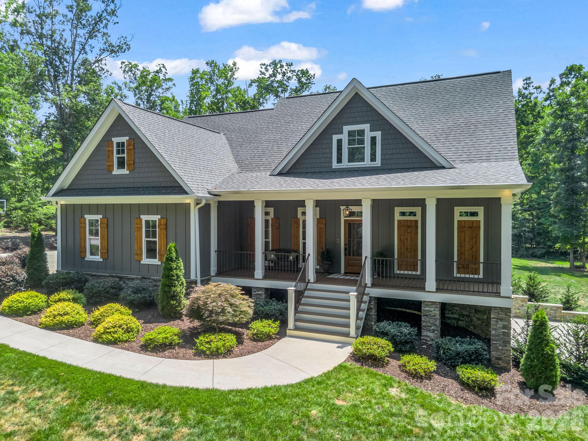 This luxury craftsman estate is nestled on 3.65 pristine, wooded acres in the highly desirable Bostic community. This spectacular 2,900+ square foot estate offers an unparalleled blend of modern luxury, high-tech connectivity, and peaceful privacy. From the durable fiber cement siding to the warm, stained wood plank porch ceilings, every detail reflects superior craftsmanship. Step inside to find breathtaking, uniform white oak flooring stretching across an open and airy floor plan. The living room serves as a dramatic centerpiece, boasting soaring vaulted ceilings accented by rustic wood beams and a magnificent, real stone gas log fireplace. Serving as a true conversation piece, the fireplace is anchored by a custom white oak beam mantle harvested directly from the property. The gourmet chef’s kitchen features premium granite countertops and opens seamlessly into a bright, inviting breakfast room—the perfect spot for your morning coffee while looking out over your private acreage. Host unforgettable dinners in the formal dining room, which features elegant coffered ceilings and a custom shiplap accent wall. A convenient main-level half bath with a sleek quartz vanity is perfectly situated for guests. The main-level owner’s suite is a private sanctuary, featuring a deep tray ceiling and a luxurious, spa-like master bathroom complete with a soaring vaulted ceiling, custom tile work, and a sleek quartz vanity. The premium white oak flooring continues seamlessly throughout the entire second floor, where you will find three generously sized bedrooms, a full bathroom with a beautiful tile floor and quartz countertop, and an adaptable bonus space perfect for an optional media room or play room. The finished basement features a private full bath with a quartz vanity and a spacious room finished with durable, commercial-grade Luxury Vinyl Plank (LVP) flooring, functioning perfectly as an optional fifth bedroom guest suite or home office. The lower level also includes over 900 square feet of unfinished space—ideal for a workshop, home gym, or massive storage. Perfect for remote work, gaming, or seamless streaming, the entire home is meticulously wired for high-speed home networking and powered by blazing-fast fiber optic internet. An attached two-car garage provides everyday convenience, complemented by a large driveway with ample parking for guests. Enjoy the great outdoors from your expansive covered front and rear porches. The back of the home features a seamless transition from the covered porch to a large open-air deck, built entirely with premium, maintenance-free Trex decking. Follow the path into your wooded acreage to discover a beautiful, deeply secluded firepit area—the ultimate spot for starlit evening gatherings. While providing a perfectly secluded retreat, this property offers incredible geographic convenience. Enjoy a peaceful countryside lifestyle while being centrally located just one hour away from the major hubs of Asheville, Hickory, and Charlotte, North Carolina, as well as Spartanburg, South Carolina.