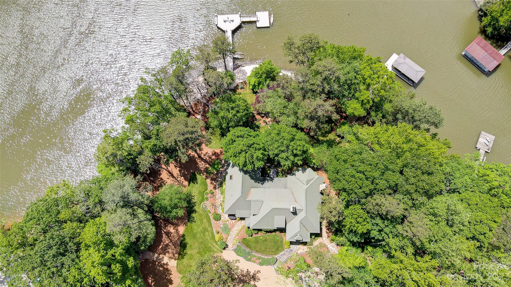 Picturesque European inspired waterfront estate w/ magnificent views of Lake Wylie! Truly a “one of a kind” peninsula lot offering gentle slope, privacy, & approx. 450’ of shoreline. Live outdoors on your massive screened porch, entertain in your professionally landscaped park, & enjoy boating or water sports from one of 2 docks. Boasting extensive 17th & 18th century architectural details: stained glass, intricately carved paneling & cabinetry, exposed beams, 3 fireplaces, imported handrails, & reclaimed wood floors.  Amazing 2 story great room opens to formal dining w/ stone fireplace. Gourmet kitchen w/ ss appliances, Wolf gas range, & butlers pantry. 2nd primary & guest bedroom on main each w/ full bath. Upstairs you will find incredible primary suite featuring sitting area & custom walk-in closet, plus huge 4th BR Suite w/ den & storage.  Charming detached "Barn" offers covered parking, workshop, exercise room, & tons of storage. Great location w/easy access to airport & Uptown.