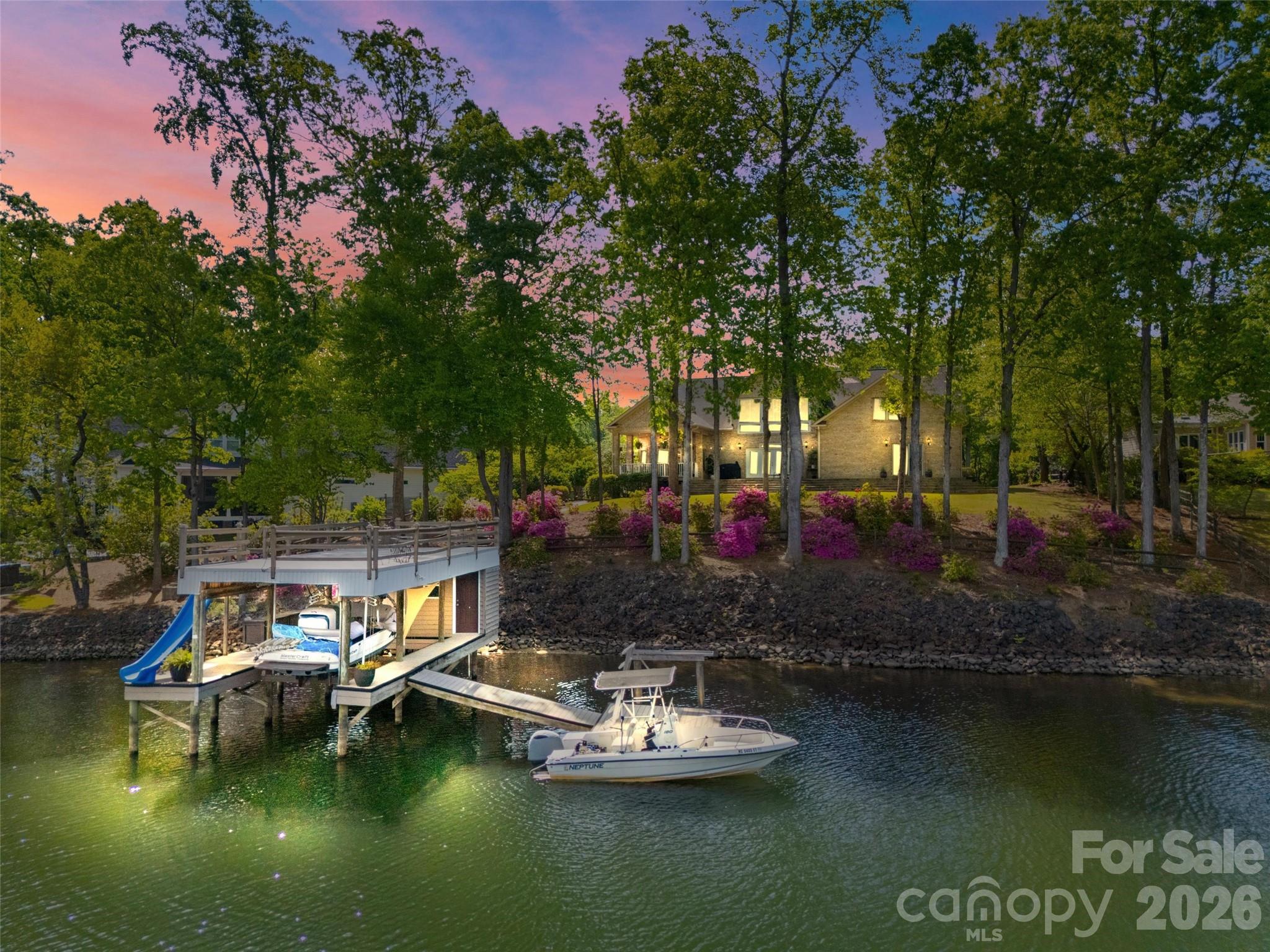Welcome to lake living at its finest on highly sought-after Johnson Road in Clover on beautiful Lake Wylie! This exceptional .69-acre flat retreat features a rare 149 feet of shoreline lined with Firecracker Azalea, paired with breathtaking panoramic lake views. Enjoy stunning sunrises from the kitchen windows and unforgettable sunsets from the back patio, creating the perfect backdrop for everyday living.

Designed with flexibility in mind, the layout is ideal for multi-generational living or room to spread out, offering space and privacy for everyone. Inside, you’ll find 9’ ceilings and beautiful engineered hardwood floors that add warmth and timeless character throughout the main living areas. The bright, airy kitchen is thoughtfully appointed with double ovens, a gas stovetop, soft-close drawers, and even a built-in trash compactor—perfect for both everyday use and entertaining. The adjacent great room showcases a beautiful custom gas fireplace, perfectly paired with built-in floating shelves for a clean, modern look.

Enjoy seamless indoor-outdoor living with three sets of French doors located in the primary bedroom, dining room, and family room, two of which feature retractable screens for added comfort and convenience.

The spacious primary suite offers private access to the back patio, multiple closets, and a luxurious en-suite bath with tall ceilings, a steam shower, and soaking tub.

Additional highlights include an oversized laundry/keeping room with sink and abundant storage, as well as a whole house fan for added efficiency and comfort.

Step outside to the covered Trex patio and take in peaceful views and a true waterfront lifestyle. The backyard showcases lush Zoysia grass both front and back, along with a custom fire pit perfect for cozy evenings by the lake.

The double-decker DEEP WATER dock is designed for both fun and function, complete with a slide, boat lift, sundeck, and floating dock. The dock offers ample storage with two deck boxes and two storage closets—perfect for keeping all your water toys and gear organized. The dock is fully permitted and truly a must-see.

Whether you’re looking for a full-time residence or a lakefront retreat, this property offers the perfect blend of comfort, thoughtful upgrades, functionality, and unforgettable views.