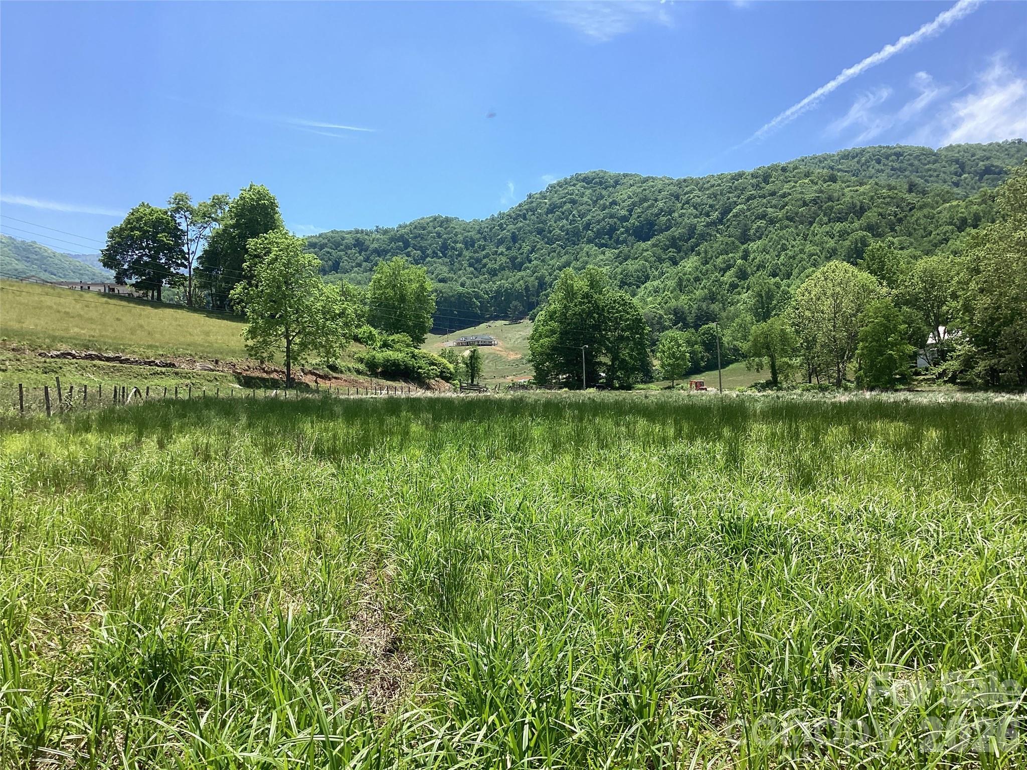 Just outside the quiet mountain town of Burnsville, NC, this 7± acre tract rests where the land begins to slow down and open up. With more than 1,000 feet of frontage along Bolens Creek Road and additional access from a private road, the property is easy to reach while still feeling tucked away in the Blue Ridge Mountains of Western North Carolina. The land itself is unusually gentle for the mountains. It is mostly flat with usable, tillable ground that has long inviting gardens, small farms, or simply room to spread out. Along the back boundary, Bolens Creek winds the property line, adding the steady sound of moving water beneath the backdrop of the Blue Ridge Mountains rising in the distance. Already perc’d for a 3-bedroom septic system, the tract is well suited for a mountain homestead, family retreat, or investment for the future.  Unrestricted land, no zoning and just three minutes outside the Burnsville city limits, your mountain land vision has room to become reality.  If you’re looking for a slower pace and natural beauty in Western NC this is an ideal location.  This is the kind of property where mornings begin with mountain views, evenings end by the creek, and the land itself gives you the space to build something lasting.