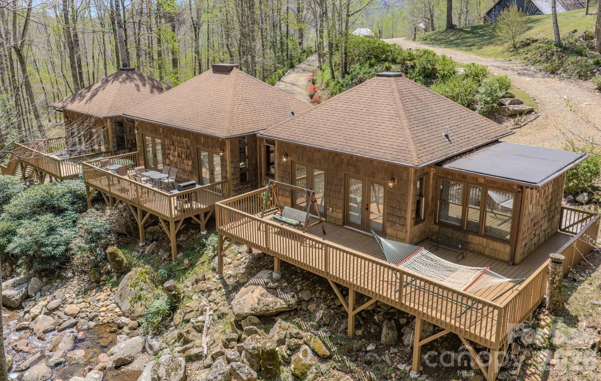 Escape to the quiet beauty of the mountains with this thoughtfully designed retreat, where peace and relaxation take center stage. Nestled in the serene landscape of Bakersville, this 2 bedroom, 2.5 bath home offers a perfect balance of comfort, privacy, and natural charm.

Inside, the inviting living space is complemented by warm wormy maple kitchen cabinetry and custom built-in benches with hidden storage blending functionality with timeless mountain character. Large windows invite the outdoors in, allowing you to take in views of the gently flowing creek while also hearing its soothing sounds from within the home creating a truly immersive, calming environment.

Outdoors is where this property truly shines! Three spacious independent private decks overlook the tranquil creek, offering the perfect setting for morning coffee, quiet reflection, or evening relaxation. A propane gas hookup makes outdoor dining effortless, while the warm-water exterior hookup provides the opportunity to create a spa-like outdoor shower experience.

A private walking trail runs alongside the creek, inviting you to stroll, unwind, and fully connect with the natural surroundings. The river rock driveway enhances the home’s organic beauty, welcoming you into a setting that feels both grounded and refined.

Whether you are seeking a weekend sanctuary or a place to fully disconnect and recharge, this property offers a rare opportunity to embrace the restorative beauty and peaceful rhythm of mountain living.