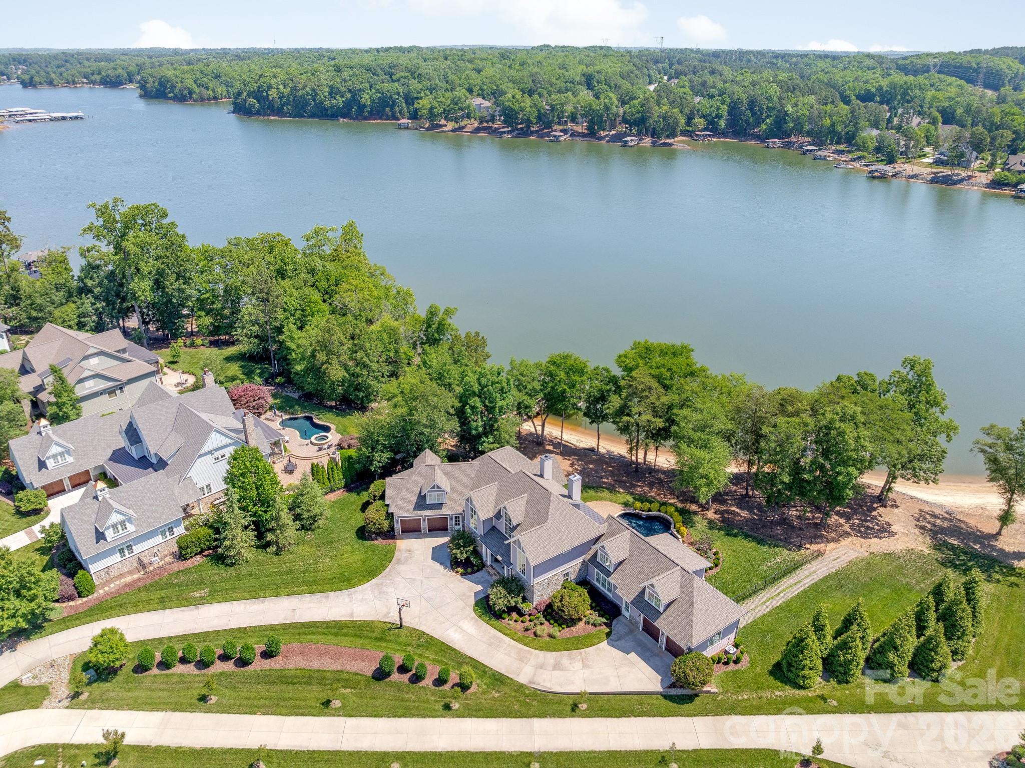 Waterfront nirvana on Lake Wylie in Belmont NC. There's such a feeling of being on vacation and escaping the daily grind when you pull into your driveway at 317 Cape August Place in McLean South Shore. Observe the luxury architecture and finishes as you walk into your custom-built home and gaze across your in-ground pool out to an expansive view of the lake. Experience the joy of walking to your covered boat dock, lowering your watercraft with the 7000# Tide Tamer lift into the deep water of Lake Wylie, and feeling the breeze flow across your face as you journey the main channel and hidden coves. Dip into your in-ground pool when you return and enjoy a beverage while the sun warms your soul. Dinner is a few steps away with a built-in gas grill under the covered terrace. All the while enjoying broad views of the lake from your flat waterfront lot. If feeling the warm sand between your toes or launching your paddle board calls you, then just walk into your back yard to your own private beach and over 280 feet of shoreline. Such an incredible combination you have found in this property - a level lot and a natural beach of your own! Custom designed to the lot being wide rather than long, the floor plan was drawn so most of the rooms have a view of the lake. With a wide rather than long room layout, the lake becomes your constant piece of art to your eyes, with the pool lights being an evening piece of jewelry glittering in your view. Another special aspect of this property is what could be a second living space or very private office space. Located above one of the two garages, this space is connected to the main home yet features an exterior door for private access. Offering its own full bath, view of the lake, bedroom and flex room, this space can accommodate so many needs. It even has access to one of the garages. Daily living and entertaining are a joy when you bring your inner chef to life in the newer remodeled kitchen. Challenge yourself with any recipe with your gas cooktop, built-in side/side freezer/refrigerator, and wall oven/micro combo. The huge island with farm sink, plus the floor to ceiling cabinetry makes prep, serving and clean-up a task to be enjoyed. Owners are pampered when arriving or leaving with mud room access directly into the expansive custom owner’s closet, then into your spa bath. Breathe deeply as you rest in your bedroom with a lake view through the wall of windows. Experience warmer nights with direct access to the covered terrace and the pool. Upstairs there are three bedrooms with three full baths that offer so much convenience for those who live there. Exercise, play and all-around fun is easy with the large rec room on the second level. Gorgeous newer lighting decorates the home and sparkles your inner glow. McLean South Shore is a prestigious custom waterfront community located near the quaint town of Belmont NC. Access to work, restaurants, theater, and more shopping in greater Charlotte NC region is minutes away via highway access from Belmont. Satisfy your travel desires with quick and easy drive to the Charlotte Douglas International airport. Living in McLean feels quiet, yet offers so much around this location. An easier life awaits you at 317 Cape August Place. Schedule a showing today to see for yourself!