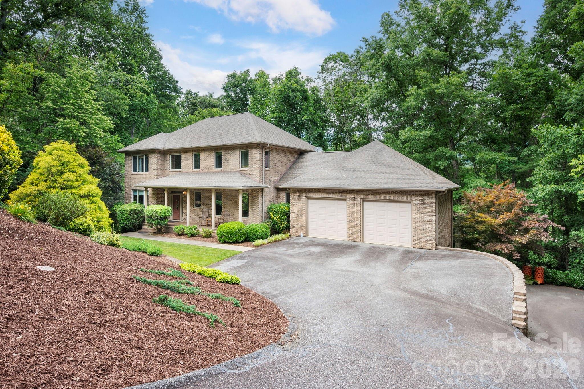 Tucked away in Fairview's sought-after Garren Creek area, this private 1.32-acre property offers the perfect balance of mountain tranquility and convenience, approx. 20 minutes from downtown Asheville and just minutes to Blue Ridge Parkway trails, Hickory Nut Gap Farm, local restaurants, and grocery options. The spacious home features two oversized 2-car garages plus an open-concept anchored by a chef's kitchen with Bosch and Viking appliances, an oversized island, and an abundance of cabinetry. Enjoy multiple outdoor living spaces including a covered rocking-chair porch, screened deck, and open deck surrounded by trees. Upstairs, the primary suite offers a large walk-in closet, soaking tub, and walk-in shower. The finished basement includes a den with a gas fireplace and projector plus a second primary suite. Additional highlights include an EV charger, tankless water heater, two laundry rooms, and a low-maintenance brick exterior in the AC Reynolds district.