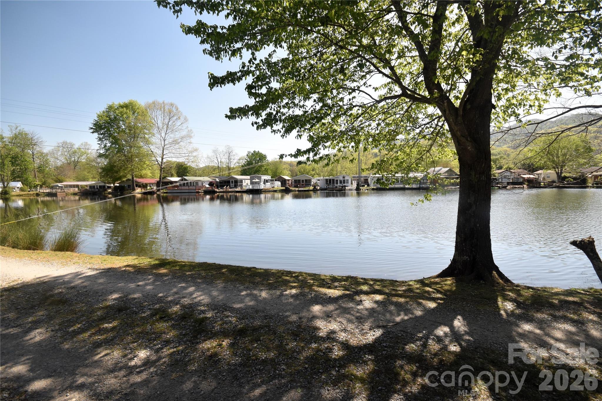 Enjoy the sounds of water music as this home is surrounded on both sides by the rushing Jonathan Creek out back and the lake frontage out front. Enjoy trout fishing, wildlife watching or just relaxataion.  Living area and king size bed are next to the windows to enjoy the creek sounds.  The dining room and kitchen you can enjoy watching the ducks swim in the lake out front.  You can also sit out on the screen porch, enjoy the separate kitchen area while having breakfast coffee, or evening drinks.  Being sold completely furnished and ready for you to start enjoying the cool summer temps.  Per the sellers this home had no flood damge from Hurricane  Helene.
Brand new roof installed October 2025 by David's Roofing Contractors  The porch kitchen has a gas stove, refrigerator and a sink.