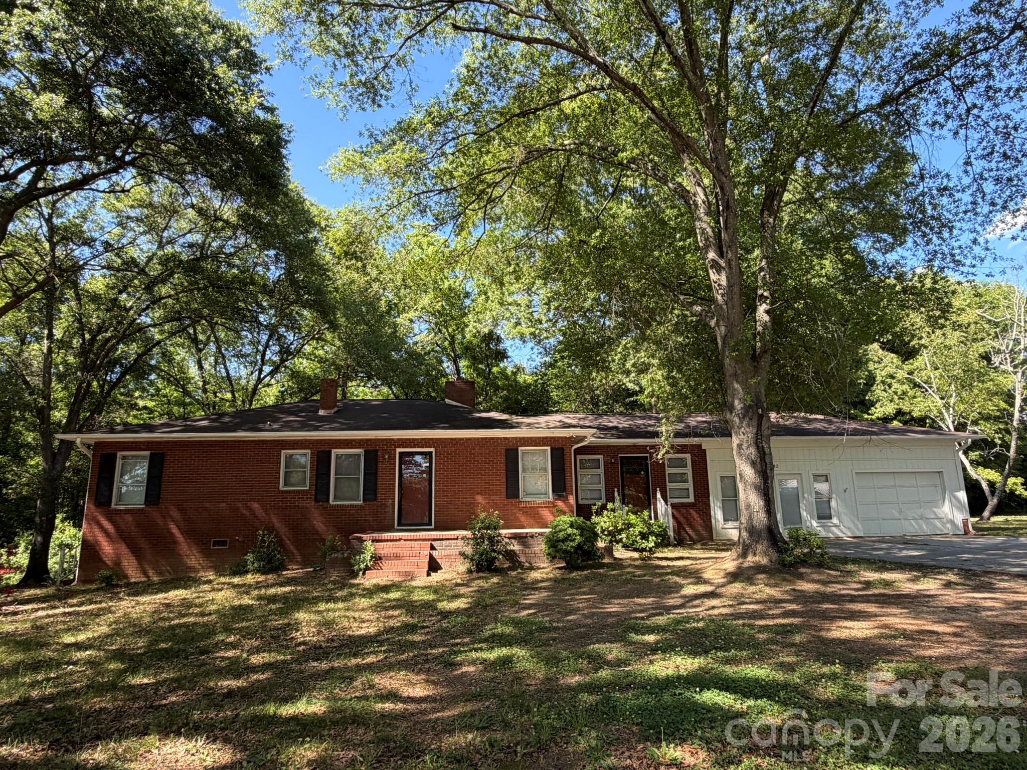 Ultimate potential awaits in NE Gaston County! This unique property features 14 total acres split across 2 parcels, boasting 427 feet of road frontage just south of the Lincoln County line. The front 3.3-acre parcel (164346) features a classic, one-family-owned brick ranch (built in 1953) being sold "as-is." Packed with original character, it features gorgeous hardwood floors throughout the hallway, living room and all 3 bedrooms, and a living room with original pine paneling, French doors, and a cozy masonry fireplace with propane logs. A partial garage conversion serves as a spacious unheated rec room with a door opening to the back yard, leaving a 1-car attached garage intact. From the hallway, there’s access to the partial walk-out basement for storage or for a potential workshop. The home, with central heat and air via heat pump, is livable and, in its most recent history, has been professionally managed as a rental. It is now vacant and ready for your cosmetic updates and TLC. Behind the house sits the second parcel (164345): 10.712 wooded acres partially bordered by a creek at the rear. GIS shows no flood plains or utility easements. The wide lot extends almost all the way over to the neighbor’s driveway on the right. After purchasing, you can keep it all together for a massive private estate, or utilize the wide road frontage to add an easement to access the rear acreage. Enjoy peaceful country living while maintaining commuting convenience: only about 1/2 mile to Hwy 27; approx. 4 miles to Stanley dining and shops, about 10 miles to Lincolnton (shopping, dining, Atrium Hospital), or, for airline travel, it’s just a 19-mile drive to Charlotte Douglas International Airport.