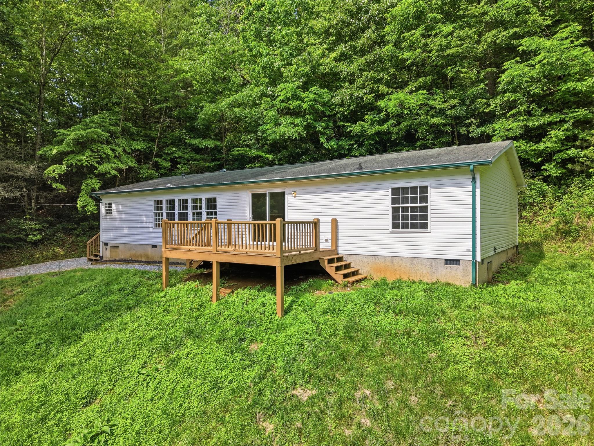 Nicely refreshed mobile home on 6.0 unrestricted acres minutes from Sylva. This spacious 3 bedroom 2 1/2 bath modernized doublewide manufactured home offers modern upgrades, and scenic surroundings.  Experience the tranquility and privacy of this expansive 6.0-acre unrestricted lot, perfect for outdoor activities and enjoying nature. The large open floor plan offers plenty of space for entertaining, featuring new luxury vinyl tile throughout and a cozy wood-burning fireplace for relaxing evenings. • Primary ensuite thoughtfully separated from two additional bedrooms and bathroom for added privacy • Front deck and a large, rolling front yard ideal for gatherings or leisure • Storage building provides ample space for tools, equipment, or hobbies • Modern appliances including a new refrigerator, gas stove, washer, and dryer • Freshly painted interior, ready for your personal touch • Close to Sylva, Waynesville, Great Smoky Mountains National Park, and Blue Ridge Parkway This home combines contemporary updates with classic comforts in an unbeatable location. Don't miss the opportunity to own your own slice of paradise just minutes from top attractions and natural beauty.