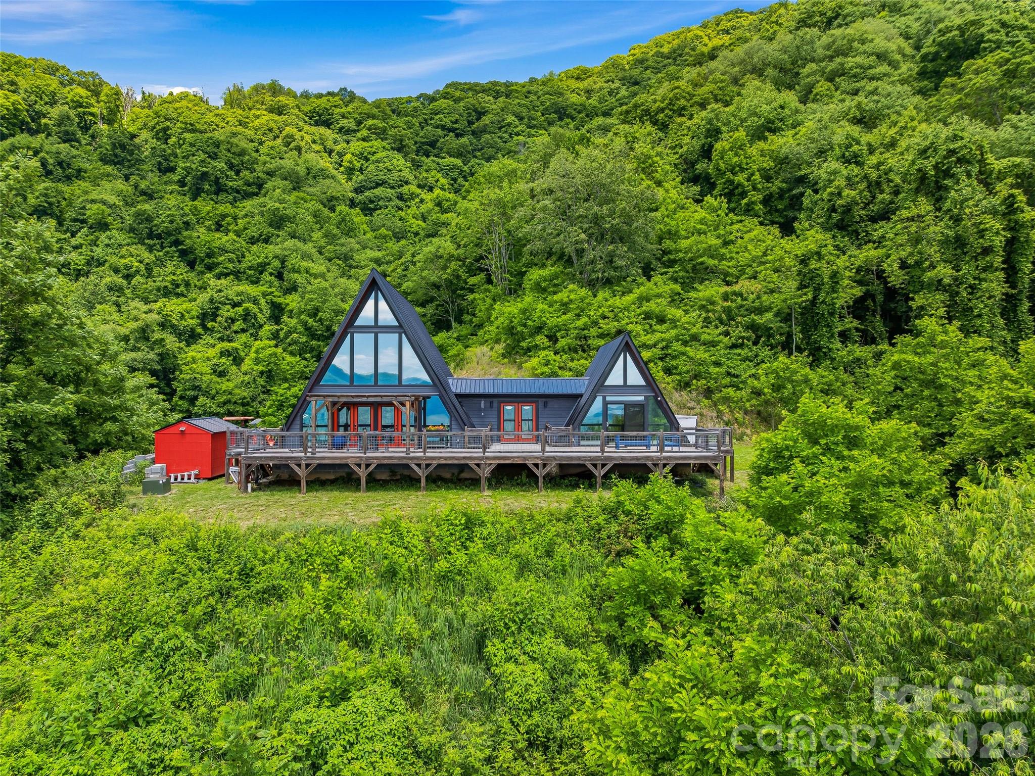 Nestled into the mountainside at just over 3,600 feet in elevation and protected by the ridgeline above, this custom-built A-frame is a rare blend of privacy, craftsmanship, and breathtaking long-range mountain views. Situated on **58 unrestricted acres**, the property offers an exceptional combination of modern mountain living and expansive land ownership. Completed in 2021 and intentionally overbuilt with quality and durability in mind, the home offers just over 1,700 square feet of thoughtfully designed living space with 3 bedrooms, 2.5 baths, and a loft overlooking the main living area.

A dramatic wall of windows serves as the focal point of the home, filling the interior with natural light while framing the surrounding mountain landscape. The heavily tinted glass enhances year-round comfort and energy efficiency without sacrificing the views. The open-concept design seamlessly connects the living, dining, and kitchen areas, creating an inviting space for both everyday living and entertaining. In the kitchen, solid wood custom cabinetry is paired with leathered granite countertops, offering a timeless blend of warmth, character, and craftsmanship. The loft above provides flexible space for a home office, reading retreat, or additional guest accommodations.

Beyond the home, the acreage offers an exceptional sense of privacy and the opportunity to enjoy your own mountain estate. The property features the potential for an additional homesite, creating flexibility for a guest home, family compound, or future expansion. The expansive acreage invites exploration, recreation, and the creation of trails, all while enjoying the peace and seclusion that only a property of this scale can provide. Built with longevity and resilience in mind, the home features hurricane strapping and a reinforced concrete-filled block foundation.

Modern conveniences have not been overlooked, with an EV charger, RV-compatible outlet, and generator port already in place. Whether you're seeking a full-time residence, refined mountain retreat, or legacy property to be enjoyed for generations, this one-of-a-kind offering delivers a rare combination of quality construction, unrestricted acreage, and an unforgettable mountain setting. Enjoy cool summer evenings, refreshing mountain air, and panoramic views from an elevation of over 3,600 feet—all while remaining within easy reach of Canton, Waynesville, and Asheville.
