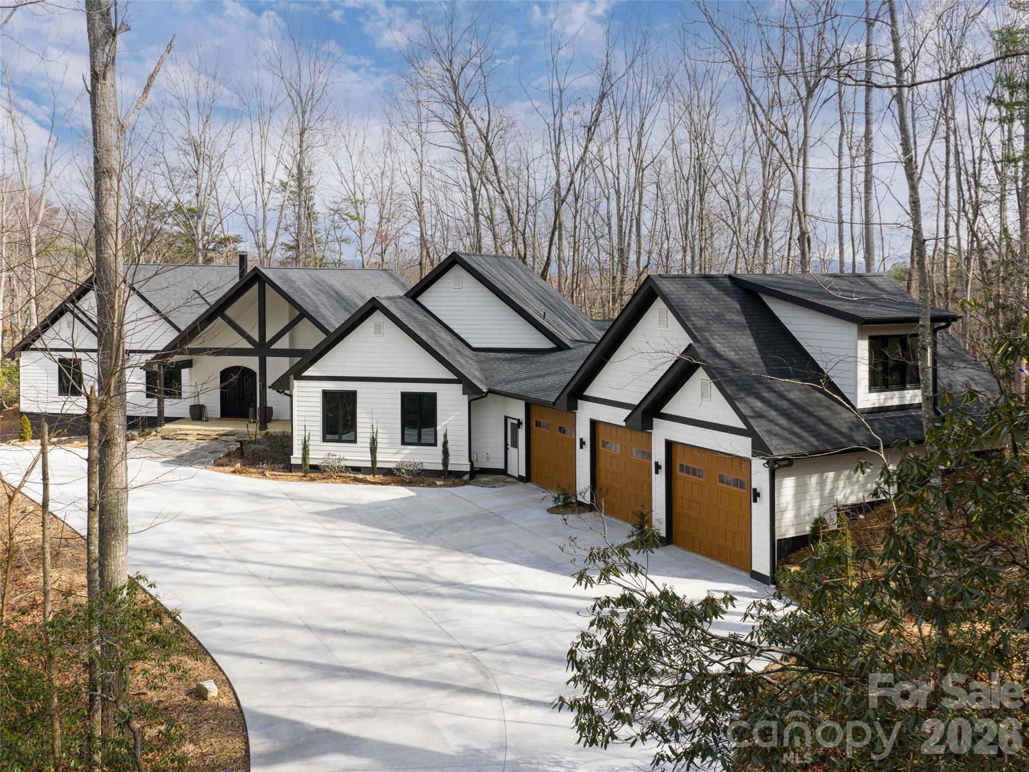 Experience the pinnacle of mountain living in this meticulously reimagined estate, where 10 natural, private, low-maintenance acres serve as your personal gateway to Pisgah National Forest. More than a renovation, this is a masterclass in craftsmanship and quiet luxury. The interior glows with natural light through new wood windows, highlighting regenerative Seringa wood flooring and Brazilian black slate tile. The chef's kitchen is a culinary showpiece featuring Brazilian granite, a Thor cooktop, and GE Cafe double ovens with warming drawer. Retreat to the luxurious owner's suite, a private sanctuary designed for ultimate relaxation with a private deck, spacious his and hers closets, and a spa-like ensuite with soaking tub and walk-in shower with dual shower heads. The 470 sq. ft. gym, located above the garage, is heated/cooled, bringing the total heated living area to 4,436 sq. ft. Outside, expansive new decking and a screened patio with a natural fireplace offer 180-degree winter views and summer shade. A meandering creek, walking bridge, 2 large and versatile barns, and a pasture complete this picturesque setting, and with the trails, this could be a perfect equestrian property. Modern infrastructure includes new dual HVAC systems, on-demand water heating, and a 3.5+car garage. This is a rare legacy property minutes from South Asheville amenities.  Deed restrictions allow for 2 additional single family homes, making it a perfect property for a family compound!
