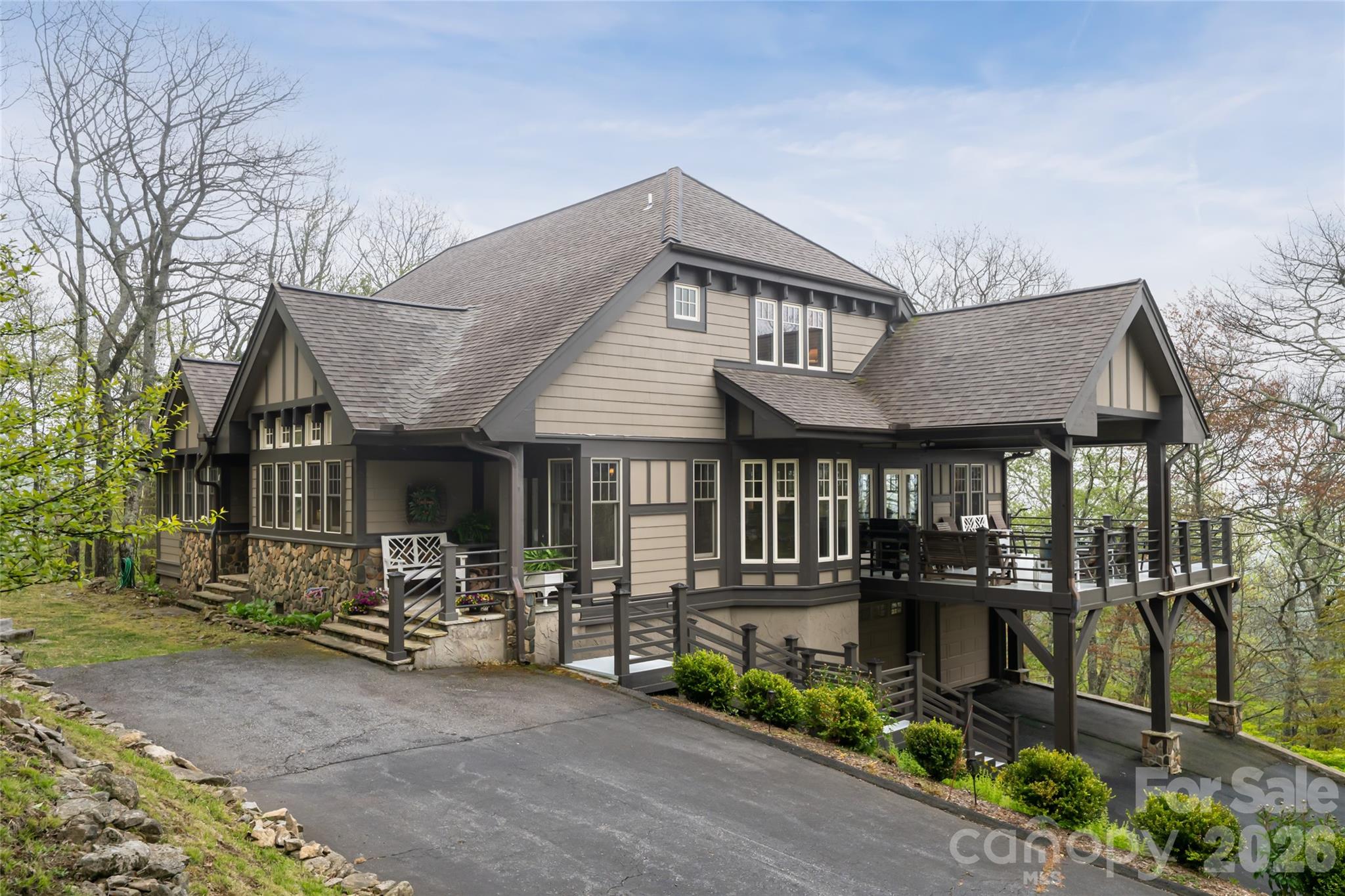 Thoughtfully designed for gathering, comfort and refined mountain living, this exceptional custom residence offers timeless craftsmanship, remarkable functionality and the warmth of a multigenerational retreat. Within the sought-after mountain community of Wolf Laurel, the home blends architectural character with carefully curated details throughout, creating an inviting environment equally suited for everyday living, entertaining and hosting extended family and guests. The heart of the home is an expansive open-concept great room and kitchen designed to foster connection while maintaining distinct living spaces through beautifully executed custom beam work and architectural detailing. Rich wood finishes, wrapped posts, handcrafted trim and exposed beams create a sophisticated mountain aesthetic balancing rustic warmth with elegance. The great room was designed for gatherings and holiday celebrations, featuring generous seating areas, a custom-built piano alcove and a seamless flow between living, dining and kitchen spaces. The chef’s kitchen is beautifully appointed with a large center island, prep sink, secondary microwave, abundant cabinetry and a charming breakfast nook ideal for casual dining. Adjacent to the kitchen, a butler’s pantry provides exceptional utility and storage, while hidden access leads to an oversized storage room designed for seasonal décor, entertaining essentials and organization. Extensive built-in storage solutions are found throughout the home, including floored attic storage, under-eave compartments, shelving systems and generous closets rarely found in mountain properties. The residence offers multiple private gathering and retreat spaces throughout. Upstairs lounge areas and loft-style sleeping quarters provide comfortable accommodations for guests and family, while every bedroom was designed with comfort and privacy in mind. Outdoor living is seamlessly integrated into the property’s design and setting. Stone walkways, retaining walls and outdoor features were crafted using rock sourced directly from the property, grounding the home beautifully within its mountain landscape. The orientation captures beautiful seasonal sunrises and sunsets, while winter views include distant ski slope lights visible from the primary suite. Expansive decks and outdoor living areas invite year-round enjoyment of the peaceful natural setting. The home is equally impressive in its construction quality and infrastructure. Much of the residence is built using poured concrete superior wall construction for enhanced durability and moisture resistance. Oversized doors, double-pane tilt-out windows and thoughtful accessibility considerations contribute to long-term comfort and functionality. A dedicated mechanical room houses multiple electric panels, heat pumps, a gas furnace, dual hot water heaters and a hot water circulator system designed to provide near-instant hot water while reducing waste. A 17-kilowatt whole-house generator with automatic transfer switch provides additional peace of mind. Additional features include a central vacuum system, fully tiled showers, wood-burning fireplaces, workshop and storage spaces, integrated speaker wiring, dehumidification systems and numerous practical enhancements throughout the home. Combining enduring craftsmanship, mountain character, exceptional storage and spaces designed for meaningful gatherings, this remarkable property presents a rare opportunity to enjoy refined mountain living in one of Western North Carolina’s premier high-elevation communities. Wolf Laurel is known as The Great Escape, offering cool mountain temperatures, dramatic scenery, hiking, skiing, golf and four-season recreation atop one of the highest ridges in Western North Carolina, just north of Asheville.