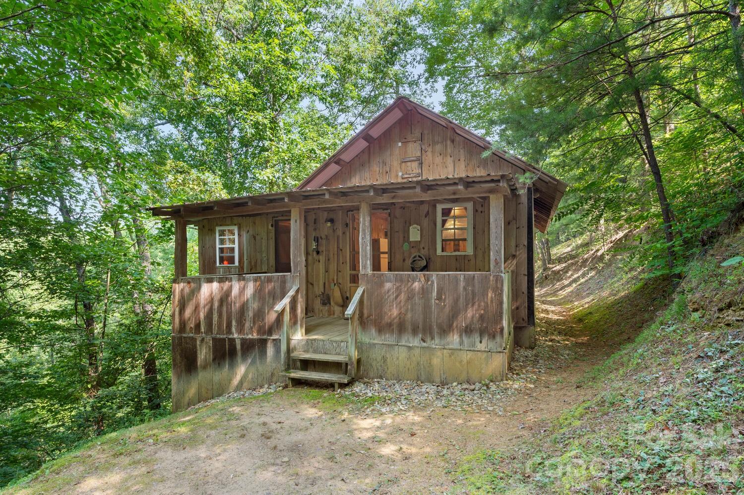 Experience a simpler way of life in this 2BR/1BA small cabin just outside of the Town of Hot Springs and close proximity to the French Broad River. Situated on 12.5 acres within a private community, this thoughtfully designed rustic tiny cabin offers a rare opportunity to enjoy mountain living while being part of a small, intentional homesteading community. Take in the mountain views from the screened porch, private backyard with firepit and picnic table in a truly peaceful setting. Shared well system and a convenient shared laundry space. Fiber internet available.  Space for a personal garden and your own backyard chickens. Opportunity for hands on learning w/experienced onsite farm owners. Cabin is on a single lane mountain dirt road - 4WD or AWD required within the community.  BY APPOINTMENT ONLY - NO DRIVE BYS PLEASE