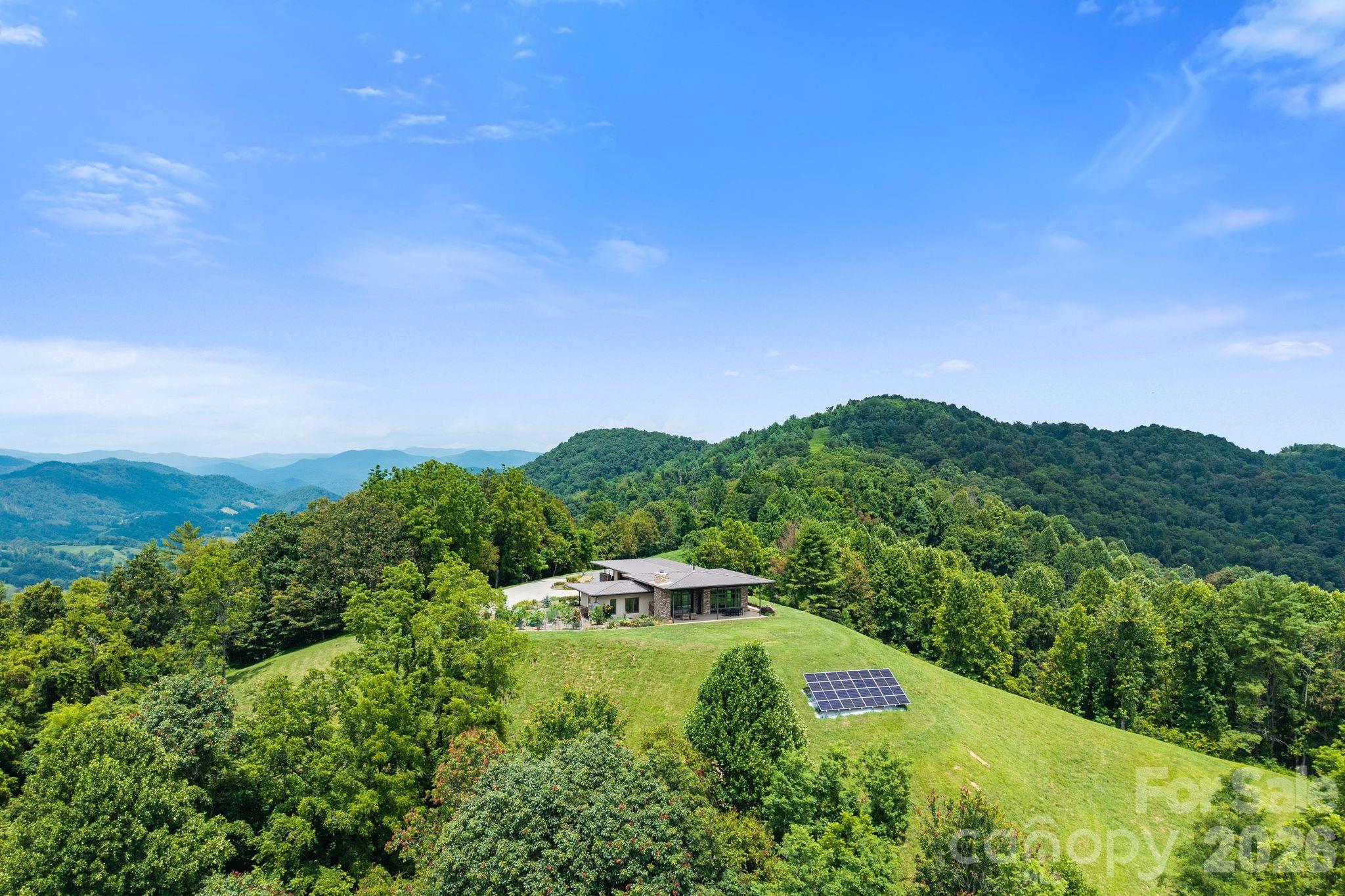 Majestic Mountain is a 114 acre retreat offering an oasis of privacy, security, self-sufficiency, and peaceful coexistence with nature. The 1.5 mile drive winds through the regenerative cattle farm to the south facing main house with year round long range 360 degree layered mountain views from an elevation of just under 3000 feet. Relax on the covered porch with a roaring fire in the beautiful outdoor fireplace. Enjoy stunning views of Mt Pisgah, Mt Mitchell, and Asheville. The open concept floor plan, 13 ft ceilings, and 10 ft windows make the home feel expansive. The main house boasts 12” autoclaved aerated concrete walls and an 8.8KW solar array with batteries and generator backup. Enjoy daily hikes on the trail system throughout the interior of the property with multiple potential build sites. The property also features a fully renovated 2BR/1BA guest house with the same astounding views, open floor plan and attention to detail. FOR MORE INFO: https://wncmajesticmountain.com?mls