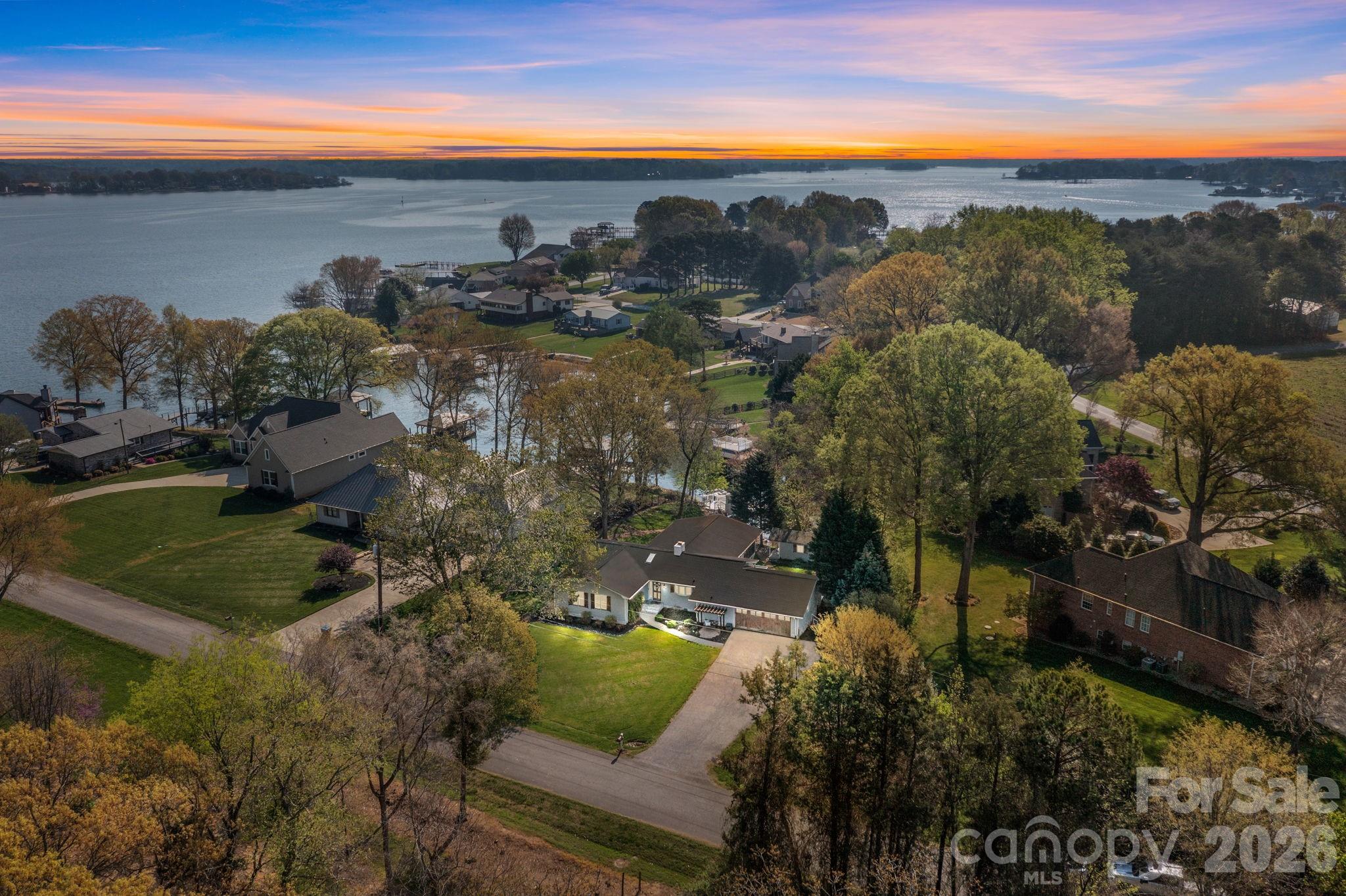 New price on this Lake Norman waterfront retreat! Tucked inside a quiet, protected cove just off the main channel, this one-level home offers peaceful country charm with the lifestyle benefits of lakefront living. Designed for indoor-outdoor living, the home features a spacious sunroom, screened porch, multiple decks, fenced backyard with fire pit, two-tier dock, and dock house for lake storage. The seller notes the cove has been dredged, offering reliable water access and year-round enjoyment.  Inside, the home feels warm and inviting with a stone fireplace anchoring the living room. The kitchen features quartz countertops, breakfast bar, gas cooktop, and distinctive copper sink. The floor plan includes 3 bedrooms, 2 full baths, plus an office/bonus room with half bath.  A separate lakeside studio adds flexible space for a home office, creative space, hobby room, guest overflow, or private retreat. Storage is available in the garage, workshop, dock house, and beneath the rear deck. Smart-home conveniences include Ring cameras at the front door and dock, gated lake access, Wi-Fi-enabled locks, garage door, and irrigation.  With no HOA and potential short-term rental flexibility, this property offers options for a full-time residence, weekend getaway, or investment. Located in a low-traffic community ideal for walking, biking, or golf cart rides, yet convenient to shopping, dining, Little Mountain Park, and Charlotte Douglas International Airport.