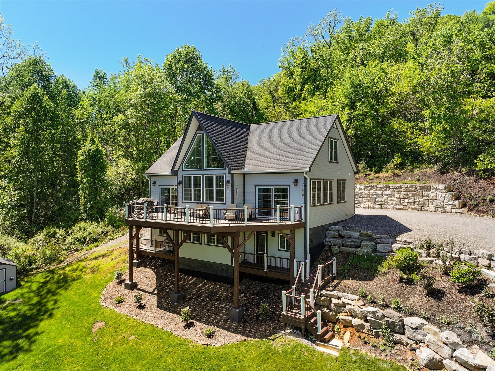 Nestled on 1.17 private acres with breathtaking year-round mountain vistas, this exceptional contemporary retreat blends luxury, craftsmanship, and modern comfort in one unforgettable setting. Located with easy access to I-40  and only 37 minutes from Asheville, 114 Nesting Ridge offers the perfect balance of privacy and convenience.

Designed to capture natural light and panoramic views from nearly every room, the home features soaring cathedral ceilings, dramatic walls of glass, and a stunning floor-to-ceiling fireplace anchoring the main living area. The open-concept design flows effortlessly to expansive Trex Transcend decks, creating seamless indoor-outdoor living ideal for entertaining or peaceful mountain evenings.

The luxurious primary suite is a true sanctuary, complete with private deck access through energy-efficient sliding glass doors, spa-inspired bath with walk-in tiled shower, jetted soaking tub, and serene fireplace views. Guest bedrooms also enjoy direct outdoor access and abundant natural light.

A striking 2nd floor mezzanine overlooks the great room below, enhancing the home’s airy architectural character. Rich design details throughout include reclaimed balcony spindles and a restored mantel from a historic 1900s residence, adding warmth and timeless charm.

The lower level offers exceptional flexibility with a spacious recreation room, office, full bath, and bonus space —perfect for guests, multigenerational living, fitness, or remote work.

Thoughtfully upgraded with premium finishes and smart-home conveniences, the property includes granite countertops, stainless smart appliances, oak hardwood flooring, tiled spa baths, energy-efficient windows and doors, recessed lighting, MagikFlame fireplace, Anran security system, Royal Celect cellular siding, and advanced construction materials designed for lasting efficiency and comfort. The home has 10 inch concrete poured walls, a stem wall through center slab for additional support.

Mature landscaping and evergreen borders create a peaceful, secluded atmosphere, while an additional outbuilding provides convenient storage.

A rare opportunity to own a refined mountain retreat where luxury living meets timeless Appalachian beauty.