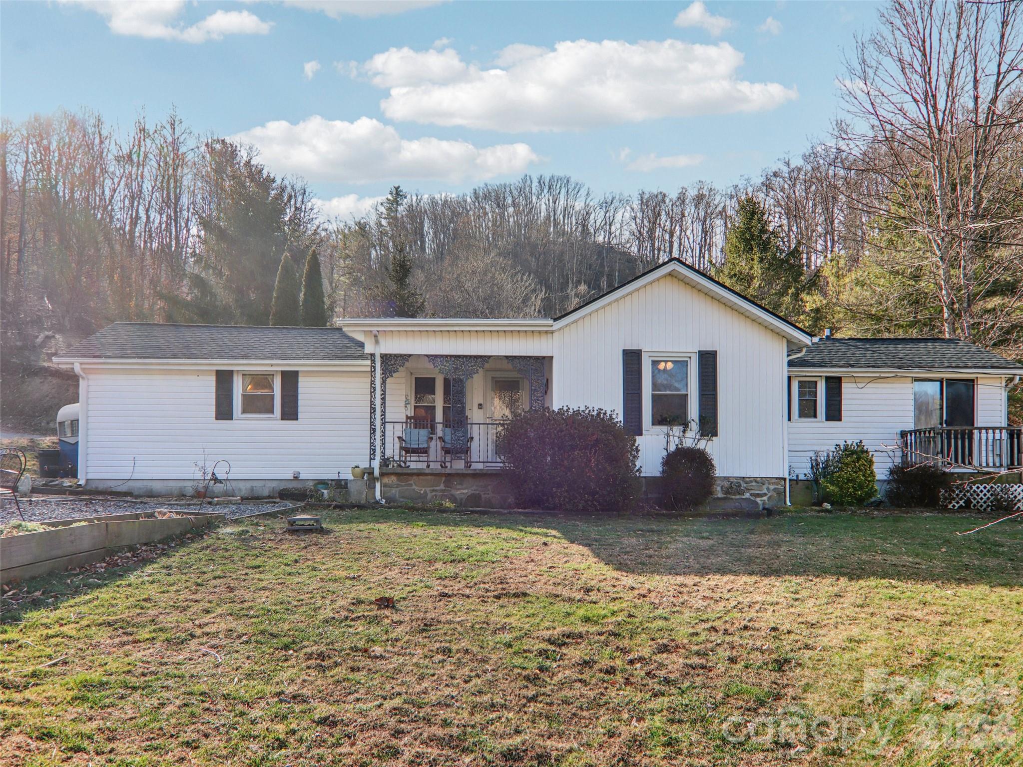 Charming single-level ranch on nearly one acre, just minutes from downtown Weaverville. This 3BR/2BA home offers comfortable one-level living in a peaceful, natural setting with level, usable land, a fenced backyard, raised garden beds, and natural water features, including a small spring in the backyard and small creeks along the front and rear portions of the property. Interior features include a remodeled kitchen (2018) with granite countertops, upgraded cabinetry, black stainless appliances, a propane range, and propane fireplace. Bathrooms have been updated, including a primary bath remodel (2018) and a hall bath refresh (2023). Enjoy covered front and rear porches, plus a well-loved wrap-around deck with access from the third bedroom. Additional features include ceiling fans, storm windows and doors, city water, and an onsite propane tank. New luxury vinyl plank flooring was added in the third bedroom in 2025. Three storage buildings provide excellent utility, including a wired workshop (not permitted). A wonderful opportunity for buyers seeking privacy, outdoor space, and proximity to Weaverville.
