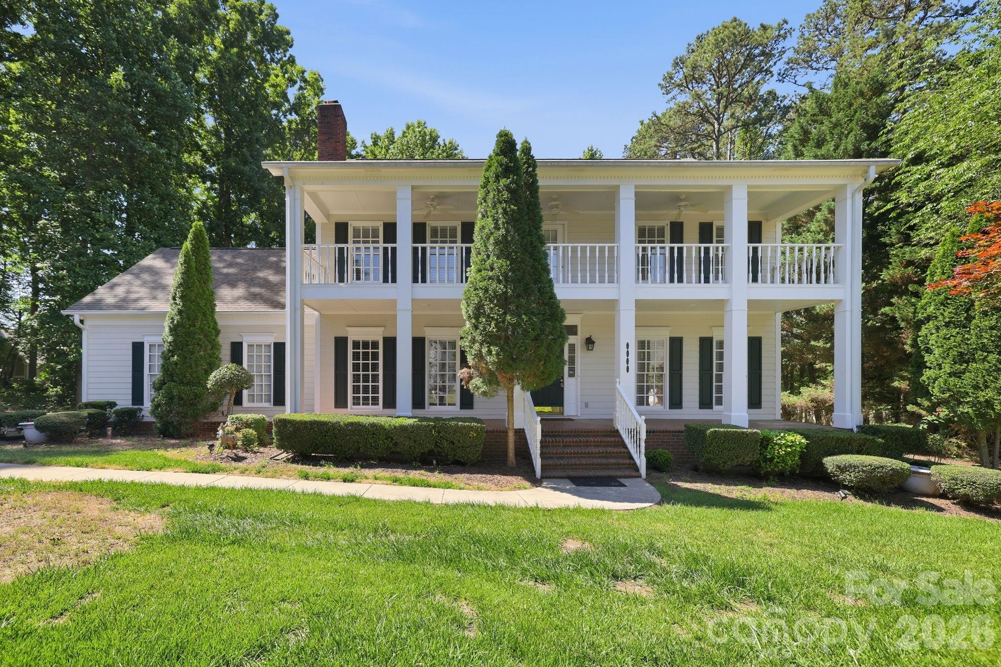 Step into timeless charm with this stately Southern Colonial, nestled in the highly sought-after Farmwood East community. With its tall, prominent columns and dual full-width porches, this home invites you to slow down and savor the moment. Enjoy sitting in your rocking chair on the front gallery or savoring morning coffee from your private second story veranda. Lovingly maintained for over three decades, the home greets you with a grand foyer, featuring a stunning chandelier and rich hardwood floors throughout. The spacious family room, anchored by a large brick fireplace, creates the perfect gathering space, while the formal sitting room flows effortlessly into an elegant dining area, ideal for hosting unforgettable evenings. The kitchen is both functional and inviting, complete with granite countertops, cherry-toned cabinetry, and a generous eat-in space. Just beyond, a beautifully added (2018) heated sunroom offers year around enjoyment with serene backyard views. Upstairs, you’ll find three additional bedrooms and a large bonus room ready to be transformed into whatever your lifestyle needs: exercise room, media room, or creative studio. The exceptional primary suite is a true retreat, featuring a private sitting area and exclusive access to the full-length veranda. The en-suite bath includes dual vanities, a soaking tub, separate shower, and spacious walk-in closet. Set on a private, flat .62-acre lot surrounded by mature trees and open space, this property offers both tranquility and convenience, just minutes from shopping, dining, parks, and more. Notable updates include: 2022 Architectural roof, 2025 Lennox HVAC, 2020 Hot Water Tank, 2025 Dishwasher, 2014 Whole Water Filter System, 2020 siding replacement (3 sides). Don't miss out on this Mint Hill Gem!
