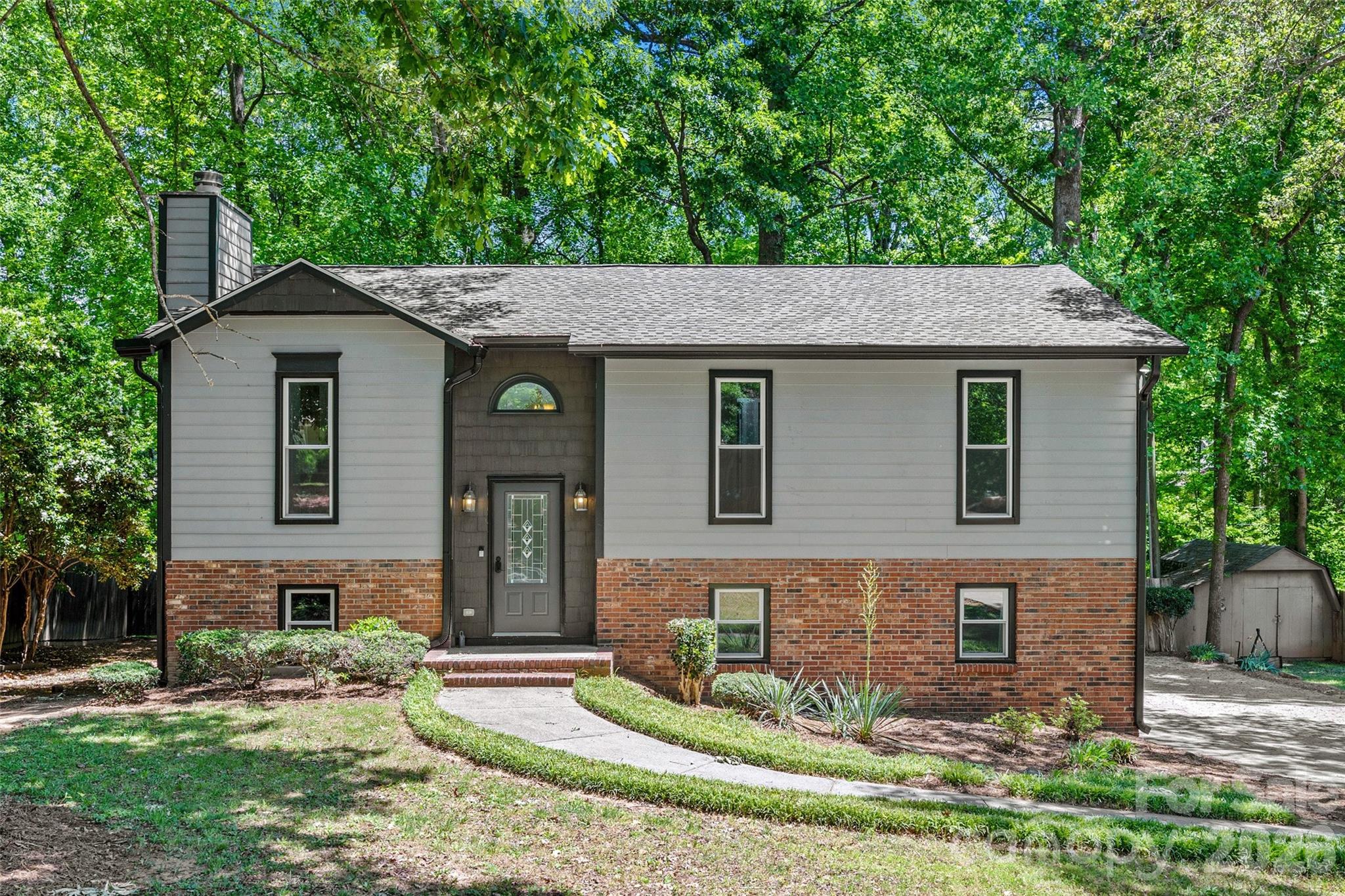 There is so much to love about this beautiful home in Fort Mill with NO HOAl!! With a unique split level design and vaulted ceilings, this home features an open, bright floorplan and a brand new kitchen with all new cabinets, quartz counters and appliances! The roof, gutters, windows and doors have also all been replaced in the past year, and the flooring and bathrooms are also recently renovated. The main level features new recessed lighting, beautiful LVP flooring, a stunning stone wood-burning fireplace, fresh neutral paint, a primary suite with a beautiful tile shower, two additional bedrooms and a hall bath. The lower level features a large bonus room with a kitchenette, a fourth bedroom, and a full bathroom with a laundry area. The 0.40 acre lot has privacy fencing and backs to woods for tons of privacy. The quiet community is just minutes from everything in Fort Mill, including the Anne Springs Close Greenway, shopping and restaurants, and is an easy commute to Charlotte. Zoned for highly rated Fort Mill Schools and low SC taxes! Don't let this beautiful home get away!