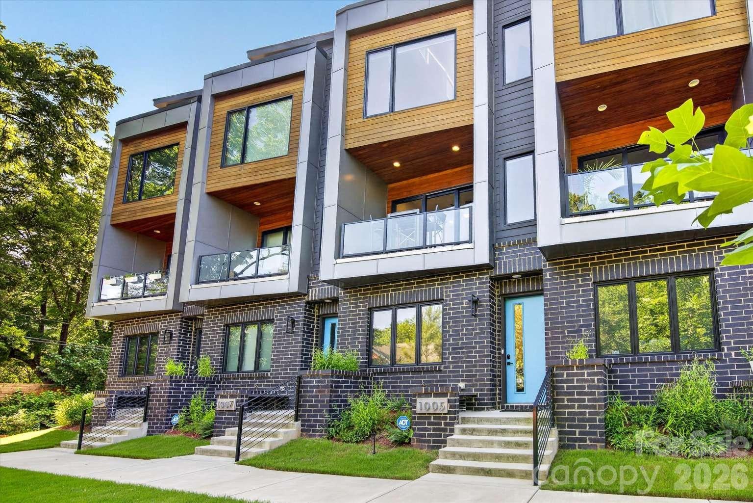 LOCATION, LOCATION, LOCATION. Welcome to your modern oasis in the heart of NoDa! This stunning 3-story mid-century modern townhome offers the perfect balance of urban energy and private tranquility. Nestled in a lush, green setting yet just steps away from the 36th Street Light Rail station, the brand-new Sprouts grocery store, and the buzzing restaurants, breweries, cafés, and entertainment that make NoDa Charlotte’s most exciting neighborhood, this home puts everything at your fingertips. Inside, every detail has been thoughtfully curated. Soaring ceilings and massive black-framed windows flood the home with natural light, while white oak hardwood floors stretch across all three levels. The designer kitchen is a true showstopper with emerald green cabinetry, brushed gold fixtures, quartz countertops, and Café GE appliances. Unique touches like a wood slat accent wall, a dramatic 3-panel sliding glass door, and a covered balcony wrapped in sleek glass and warm Thermory wood siding make this home stand out. Upstairs, the expansive owner’s suite spans the entire third floor, complete with vaulted ceilings, two walk-in closets, a gorgeous spa-inspired bath with an oversized shower, plus a flex space perfect for a home office, gym, or cozy retreat. With 2 bedrooms, 2.5 baths, and a private study, this home adapts seamlessly to your lifestyle. Practicality meets style with a one-car garage featuring tall ceilings and generous storage space. Additional upgrades include custom bidirectional blinds on nearly every window, Nest video doorbell, Nest smoke detectors, and Nest thermostats — all of which convey with the sale. And since the community was completed in 2023 by award-winning Revolve Residential, you can move in with confidence knowing you’re getting a home built with quality and vision. Whether you’re hosting friends, working from home, or strolling to dinner just steps from your door, this home is designed to impress, inspire, and makeyou fall in love with NoDa all over again.