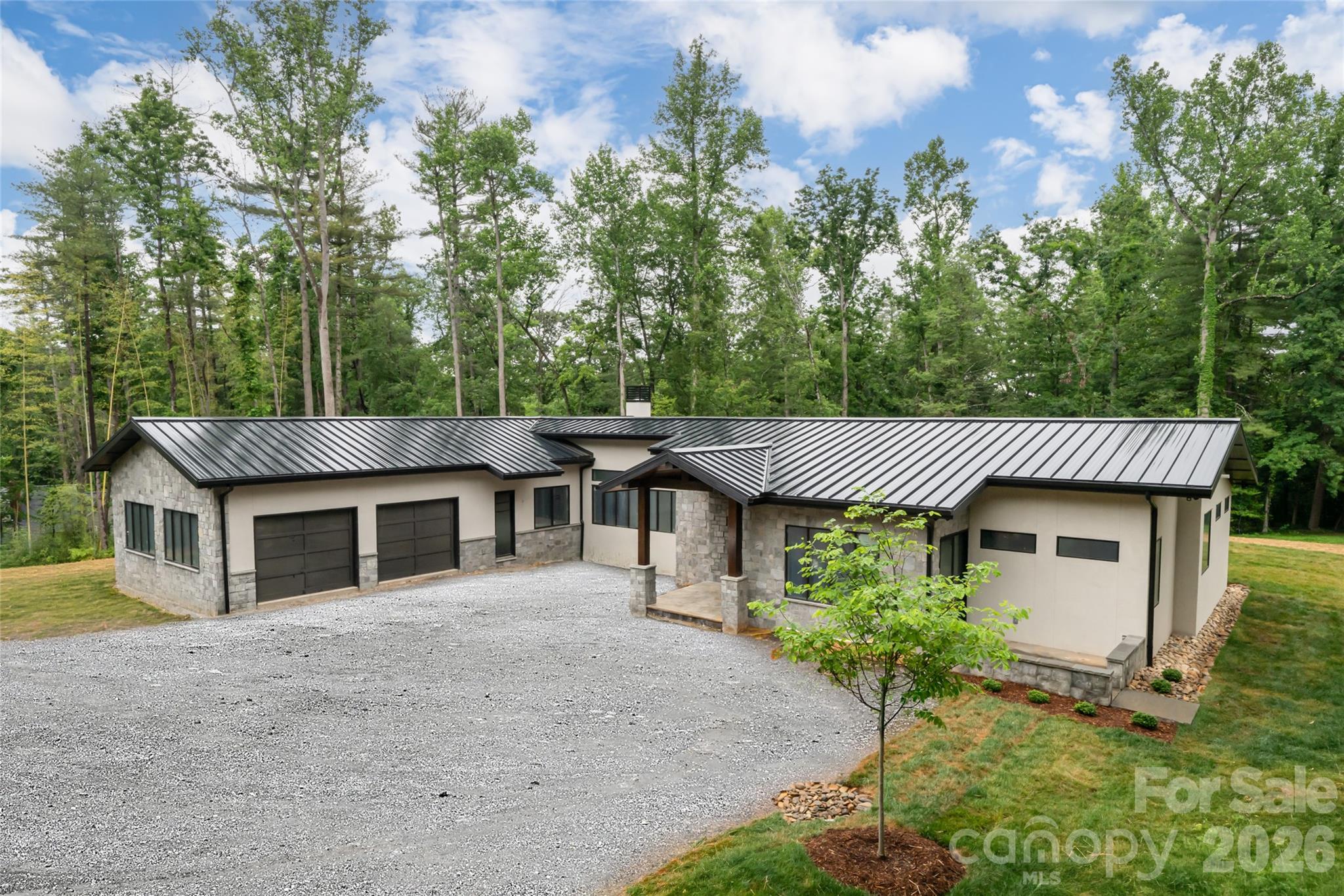 A rare opportunity awaits in the prestigious enclave of Biltmore Forest, an exceptional new-construction residence in the final stages of completion, thoughtfully designed for effortless one-level living. Set on a remarkably private lot, this custom home offers the ease of single-story living without compromise, a combination virtually unmatched in one of Asheville’s desired communities. Soaring 10-foot ceilings flow throughout, rising to a dramatic 12-foot volume in the great room, while the floor plan introduces three bedrooms and three-and-a-half baths with a seamless balance of elegance and comfort. At the heart of the home, the gourmet kitchen is anchored by a striking quartz island, apron-front sink, gas range and a full Wolf appliance suite, equally suited for everyday living and sophisticated entertaining. Multiple stone patios extend the living space outdoors, including a covered terrace with a fireplace for year-round enjoyment. A well-appointed mudroom off the garage adds everyday practicality, while the generous primary suite offers a serene and private retreat. Blending timeless finishes with the luxury of single-level living, this newly constructed residence is ready to welcome its first owners, simply arrive and experience the best of Biltmore Forest and South Asheville.