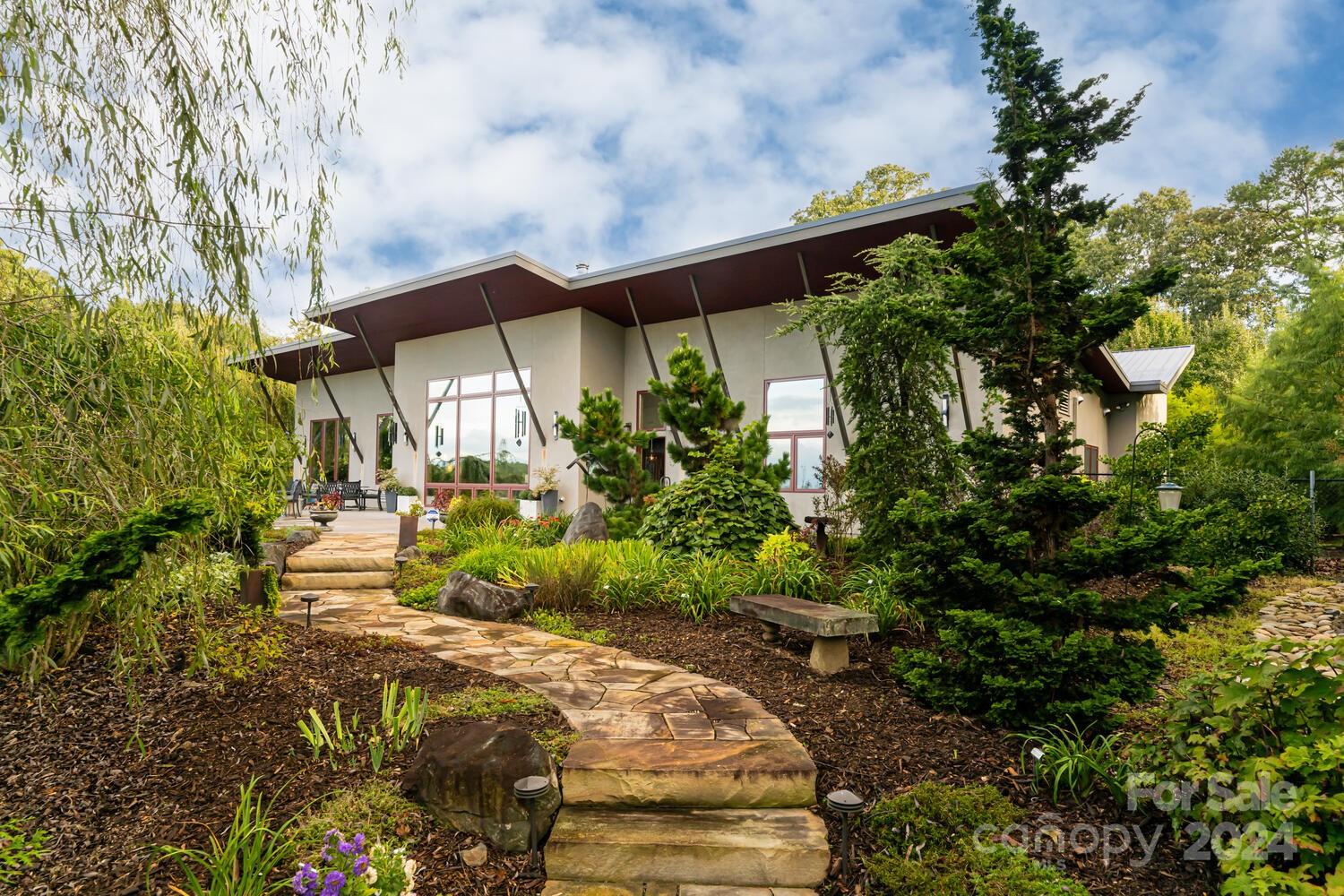 Your piece of paradise begins with this stunning, custom, energy-efficient contemporary home overlooking pastoral nature with views to Mt. Pisgah. The home marries earth & sky with its heat-gaining foundation perched on a south-facing knoll to the expansive windows & sky views. Solar panels collect usable energy while the floor captures & releases the heat. The one-level home features a split bedroom plan centered by a great room that flows to the outside in two directions. The windows to the south overlook an extensive patio & koi pond with waterfalls & dramatic landscaping. To the North is a screened porch linked to a lush shade garden. The primary suite sits to the west past a private office & laundry/mudroom. The East wing features another bedroom ensuite, 3rd bedroom, meditation room & pet room linked to an outdoor fenced area. The acreage features a natural pond, meditation circle, two out-buildings, extensive landscaping, growing gardens & orchard. Ask us for a list of features.