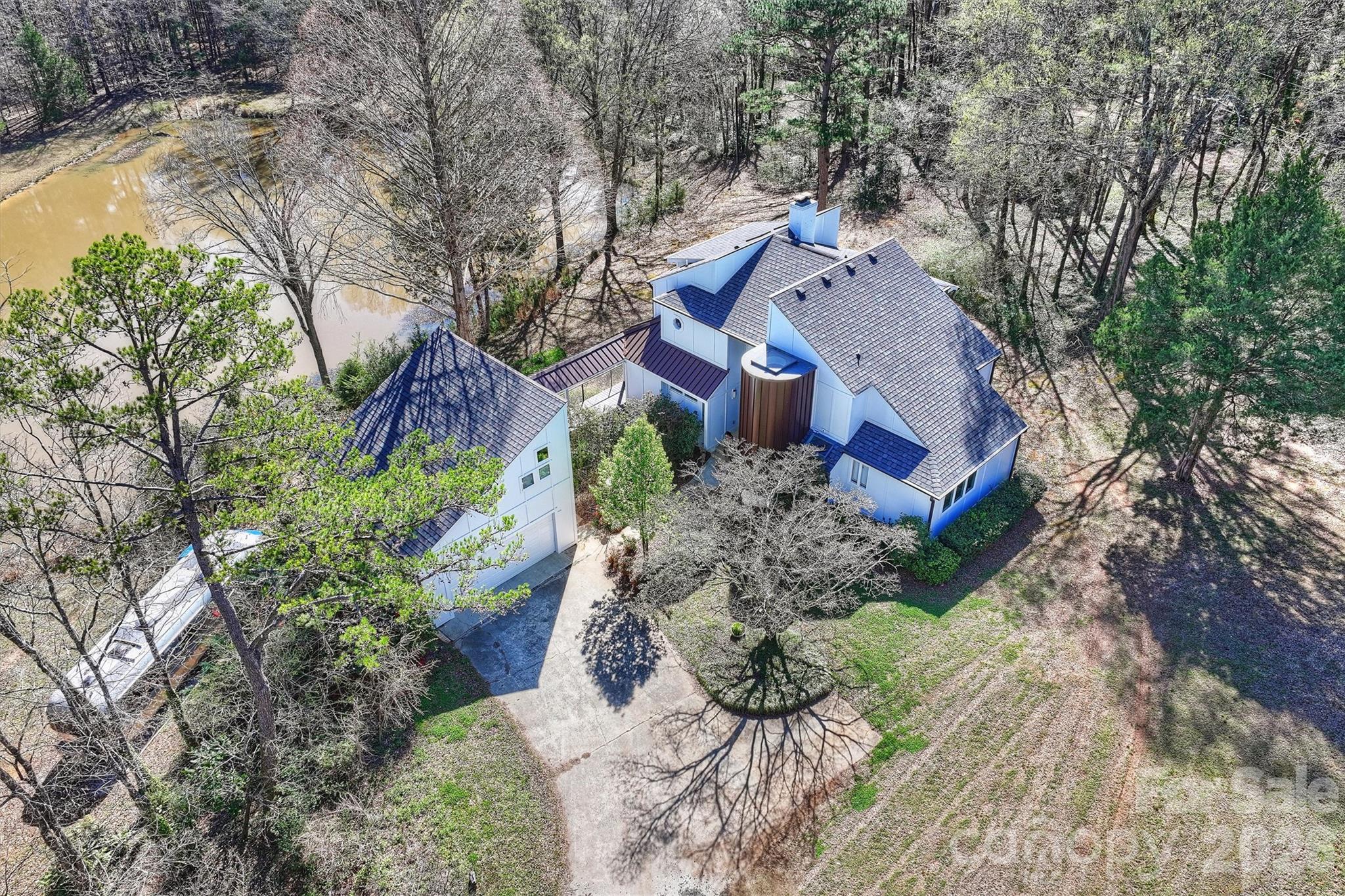 ESCAPE from nearby cities to an INCREDIBLY peaceful LAKE setting on almost 15 acres. Build a horse barn, raise chickens, grow a garden, walk the trails and skip through the creek! Add a guest house! One of a kind contemporary FIVE BEDROOM custom home with double garage and room above. The lower level with a full apartment has its own private entrance. The home has many porches which call for relaxing and enjoying the peacefulness every day. The newly expanded chef inspired kitchen with breakfast nook and windows, overlook the pond and natural areas. The inside dining room has doors to outside dining. Open concept living areas showcase dramatic two story ceilings with a fireplace. The main level includes a two bedrooms, a full bath, and a laundry room including extra storage and half bath.  Upstairs, the primary suite boasts a vaulted ceiling with skylights, a Romeo & Juliet balcony, and a spa-inspired bathroom. A second upstairs bedroom/ additional den space offers direct access to the covered upper porch. The fully updated lower level apartment adds exceptional versatility, featuring a bedroom, full bath, kitchen, living room with fireplace, laundry room with W/D, an additional refrigerator, and a spacious bonus room with a pool table! Walk out to the patio loungechair which overlooks the peaceful pond. The freshly painted two car garage has a large room above with heat and air. Perfect for a home office, studio or fitness center. Recent upgrades include a new roof, beautiful hardwood floors throughout the entire house, whole- house water filtration system, new front door and elegant copper accents. Loads of closets and storage room. The Purser-Hulsey Park and walking trails are very close. Convenient to I-485, and 20-25 minutes to uptown Charlotte. The Billard room and lower level storage room with laundry and extra refrigerator add 737 square feet to make this a 4189 sf home. There is potential to add an additional home if interested.