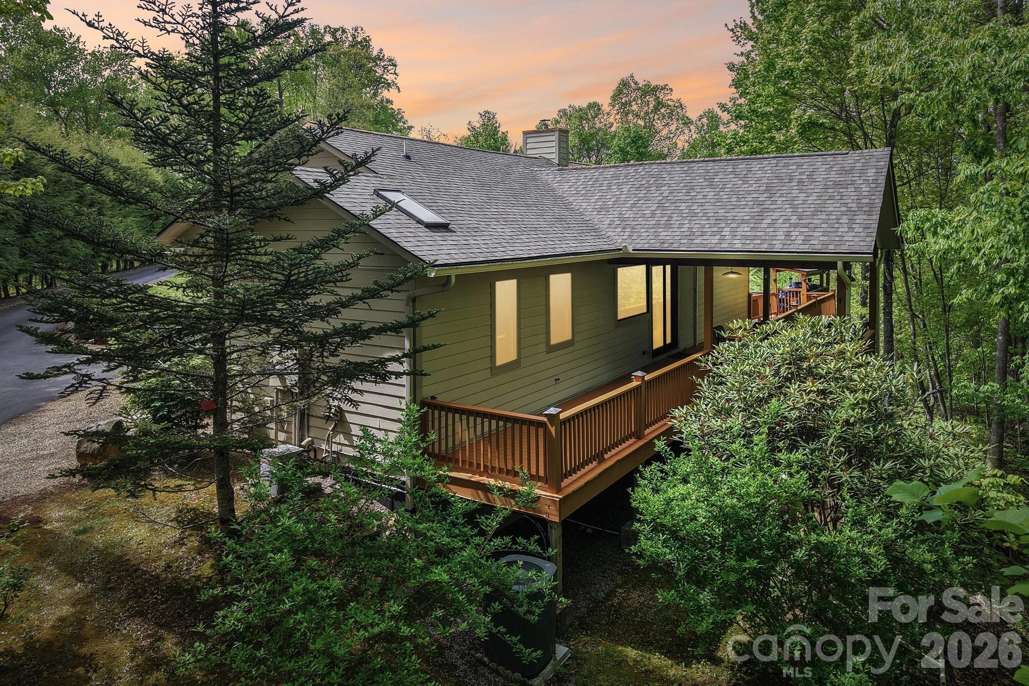 This unique, well-maintained, custom upscale mountain home sits on 3.59 private wooded acres with close mountain views, striking rock work, and numerous custom finishes. A gated entrance and paved driveway lead to the spacious, single-level residence featuring an oversized primary suite with a soaking jacuzzi tub, separate shower, large walk-in closet, and an additional closet. The split-bedroom layout places the guest suite on the opposite side of the great room, which boasts cathedral wood ceilings, an open floor plan, and a dining area. The custom gourmet kitchen is equipped with stainless steel appliances, breakfast bar, wine refrigerator, built-in pantry, and opens to a covered deck ideal for entertaining, as well as an open deck perfect for morning coffee. A fireplace with insert and abundant windows create an open, airy feel. Outside, a detached two-car garage sits near a large workshop with electricity and hot water, separate from the main house. Adjacent to the shop is a heated and cooled studio apartment with full bath and kitchenette. Additional features include a heated greenhouse with fans and skylights, camper canopy, extra carport for vehicles or recreational equipment, and a storage shed. Located in a private wooded community of distinctive homes, this property offers proximity to Mars Hill shopping, dining, and breweries, just 8 minutes to I-26 and 10 minutes from Hatley Pointe Boutique Ski Resort and Wolf Laurel Community. A truly exceptional mountain retreat.