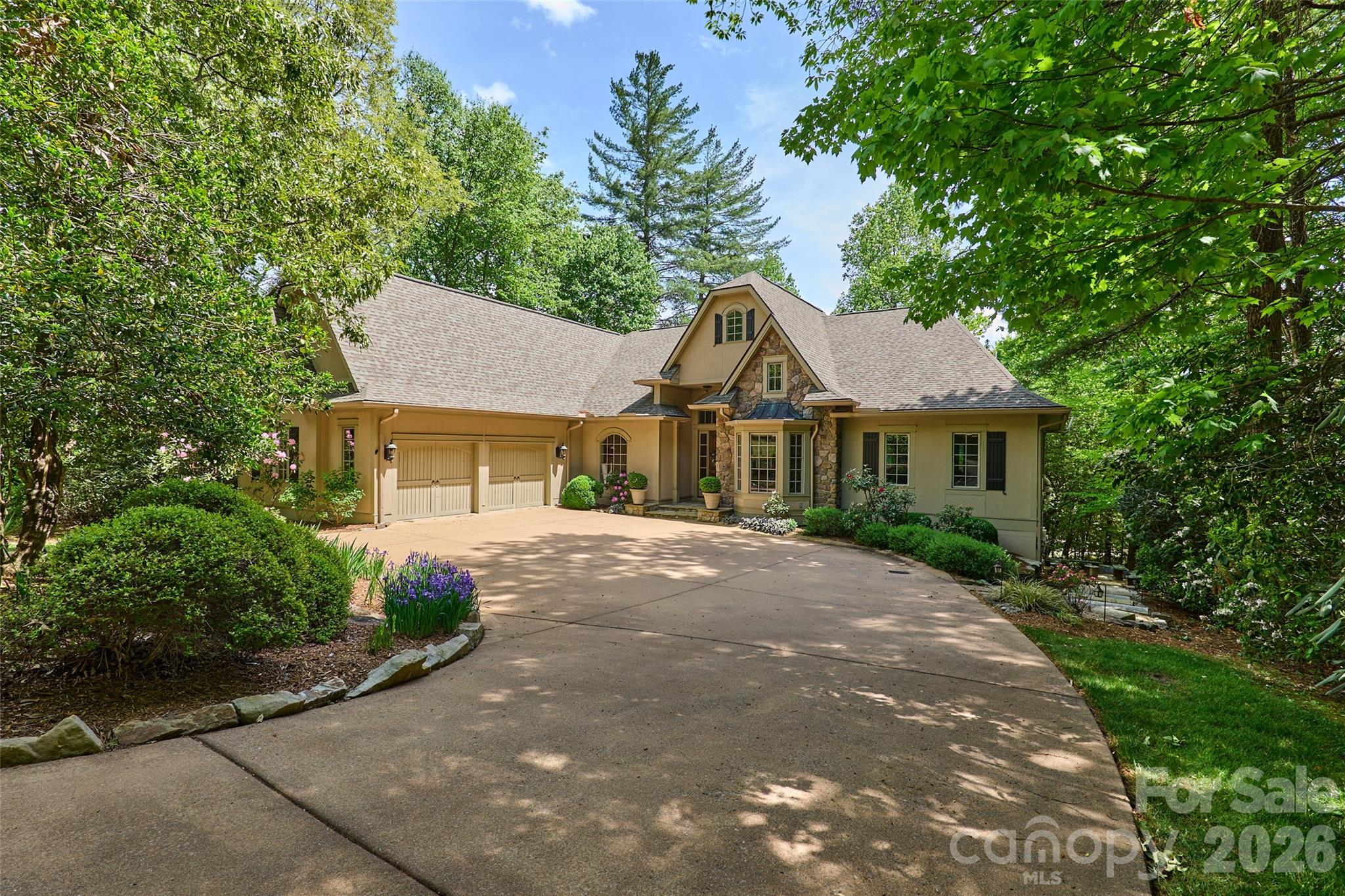 Discover refined living in this French Provincial Revival residence, beautifully situated on 1.4 private acres in the desirable Straus Park community. A stately circular driveway sets a welcoming tone upon arrival, complementing the home’s distinctive mansard roof and timeless architectural lines.

Fully updated in 2021, the main level blends elegance with modern luxury. The remodeled kitchen features granite countertops, stainless appliances, a casual dining area, and direct access to a newly built deck for seamless indoor-outdoor entertaining. The adjoining family room provides an inviting gathering space, while a formal keeping room with fireplace and a separate dining room create sophisticated options for hosting. The main level also includes a library/den, laundry room, and three well-appointed bedrooms, each with its own ensuite bath for ultimate privacy and comfort.

The third level, accessible by a graceful spiral staircase or a convenient elevator, offers treetop views and a sun-filled space ideal for a private office, art or yoga studio, or creative retreat.

Designed with flexibility and multigenerational living in mind, the lower-level functions as a complete apartment with a private entrance. This space includes a spacious bedroom and sitting area, living room, kitchenette, wine bar, and an accessible bathroom with a seamless-entry shower. A large screened porch extends the living area outdoors. Created in 2023, this level is ideal for hosting guests or separate living quarters and is plumbed for a dedicated washer and dryer.

Outdoor living is exceptional, with a stone patio for dining and entertaining, two screened balconies off two bedrooms, and tranquil wooded surroundings that offer privacy and a natural backdrop for gatherings. Whether enjoying morning coffee, hosting dinner parties, or relaxing at sunset, the home’s outdoor spaces invite year-round enjoyment.
Storage is abundant throughout the home, including multiple walk-in closets, dedicated storage rooms, and a spacious 2-car garage. 

Eco-conscious buyers will appreciate the 28 solar panels with backup Powerwall batteries, delivering efficiency, resilience, and peace of mind.

Offering a rare combination of architectural elegance, modern updates, flexible living spaces, and exceptional outdoor amenities, this distinctive home is ideal for refined mountain living with close-to-town convenience. Its thoughtful design accommodates today’s lifestyle needs, from hosting and multigenerational living to remote work and creative pursuits — all within one of Brevard’s most sought-after neighborhoods.