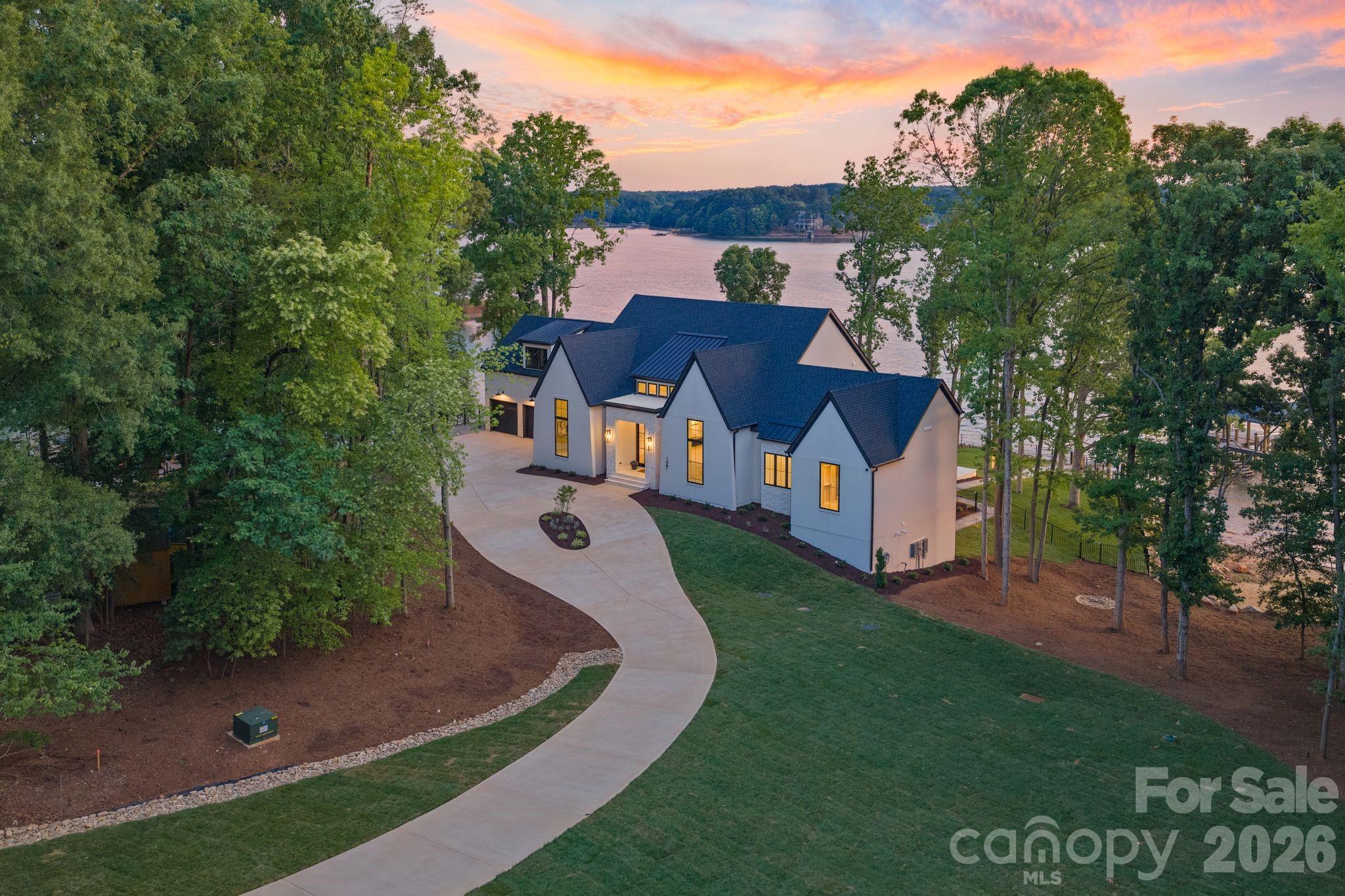 Set on a rare 1.42-acre waterfront lot with over 500’ of Lake Norman shoreline with big open water main channel views. This new custom estate built by CTR Custom Homes and designed by Sara Lynn Brennan Interior delivers a seamless blend of architectural elegance, cutting-edge smart living, and resort-style comfort, all designed for those who expect more from every detail. From the moment you arrive, the home’s modern exterior, custom landscaping, expansive driveway, and 3-car garage with epoxy floors establish presence. Inside, soaring ceilings, hardwood floors, and curated finishes create a refined yet inviting atmosphere that immediately feels like home. The heart of the home is a stunning open-concept living space framed by bronze Andersen windows that flood the interior with natural light and capture uninterrupted Lake Norman waterfront views. The designer kitchen is both a showpiece and a chef’s dream, featuring marble countertops, a 48-inch Thermador gas range, top-tier appliances, and a fully equipped scullery with a built-in app-controlled coffee system, second dishwasher, prep sink, microwave, fridge drawer and freezer drawer. The main-level primary suite is a private retreat designed for comfort and indulgence, complete with a boutique-style custom closet featuring its own island, chandelier, and in-suite washer and dryer. The spa-inspired primary bath elevates daily living with heated floors and programmable shower settings, delivering a personalized luxury experience every day. The lower level fully finished walk-out basement transforms into an entertainer’s dream and a private guest haven. With two additional bedrooms both with private full baths, a media room, flex room, rec room, custom bar, and dedicated lake bathroom, every inch of space is intentional and elevated. A climate-controlled wet storage area with epoxy floors, ensures effortless lake living year-round. Step outside and the lifestyle truly begins. Enjoy a heated saltwater pool and spa, outdoor gas grill + beverage fridge, pool-side full bathroom, and fully fenced backyard, all designed for both intimate evenings and large-scale entertaining. Your private waterfront experience is complete with your own private beach and a brand-new dock and pier with boat lift, offering direct access to the best of Lake Norman boating. This home is fully equipped with indoor-outdoor surround sound, touchscreen lighting controls, security cameras, and two tankless water heaters, blending luxury with smart efficiency. The finishing touches of custom landscaping and recently completed circular driveway ties this elevated estate together beautifully.  Take in sunset views from nearly every room or from the multiple patio areas. Additional features include, custom laundry rooms on both floors, custom lighting controls, indoor/outdoor surround sound, and security cameras. Located near Lake Norman State Park, marinas, golf courses, and top dining destinations, this property offers both privacy and convenience, with easy access to Mooresville and Charlotte. No compromises. Just elevated living.