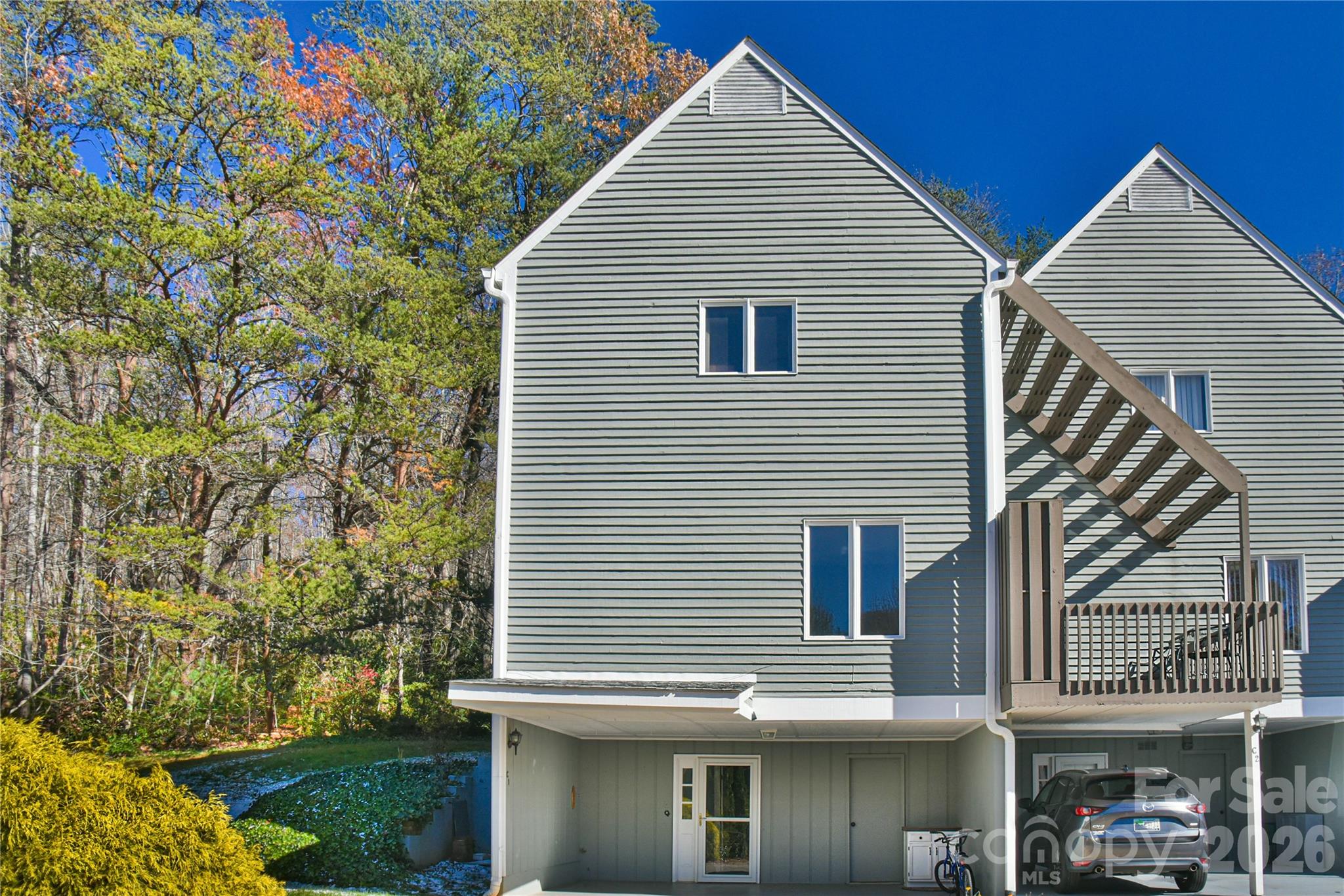 MOTIVATED SELLERS. A Sunlit Corner Retreat in The Lynx – Wrapped in Woods, Light, and Mountain Views! Tucked into a quiet corner of the beloved Lynx Condominiums, this 3-bedroom, 2.5-bath condo nestles among the trees, where sunlight pours through tall windows and mountain breezes drift across the porch. Just minutes from downtown Black Mountain and the peaceful path around Lake Tomahawk, this home offers the rare blend of maintenance-free living with the soul of a woodland retreat. Inside, the rooms feel softened by light—cascading through oversized windows and gathering in the bright 3-season room, where the boundaries between indoors and nature blur. The thoughtful galley kitchen anchors the home, while the ground-level bedroom provides comfort and ease with its own bath, stand-up shower, and nearby laundry. Upstairs, the primary bedroom opens to quiet mountain views—a gentle reminder each morning that you are living in the embrace of the Blue Ridge. Step onto the mid-level porch to linger in the sun, surrounded by treetops and birdsong. A peaceful back patio extends the living space, perfect for slow evenings or quiet conversation. With 2-car covered parking and a storage closet in the carport for all the extras—bikes, gear, and seasonal items—life here feels effortless. The community itself is warm and welcoming, where neighbors wave from their porches and summer afternoons are best spent at the community pool just a short walk away. With the Black Mountain Golf Course steps from your door and the ease of low-maintenance living, this is a place where lifestyle and location come together beautifully.
Whether you seek a serene primary residence or a thoughtfully located second home, this corner retreat offers both belonging and escape. And for added peace of mind, it comes with a one-year warranty. A place to breathe. A place to settle in. A place where nature, comfort, and community meet.