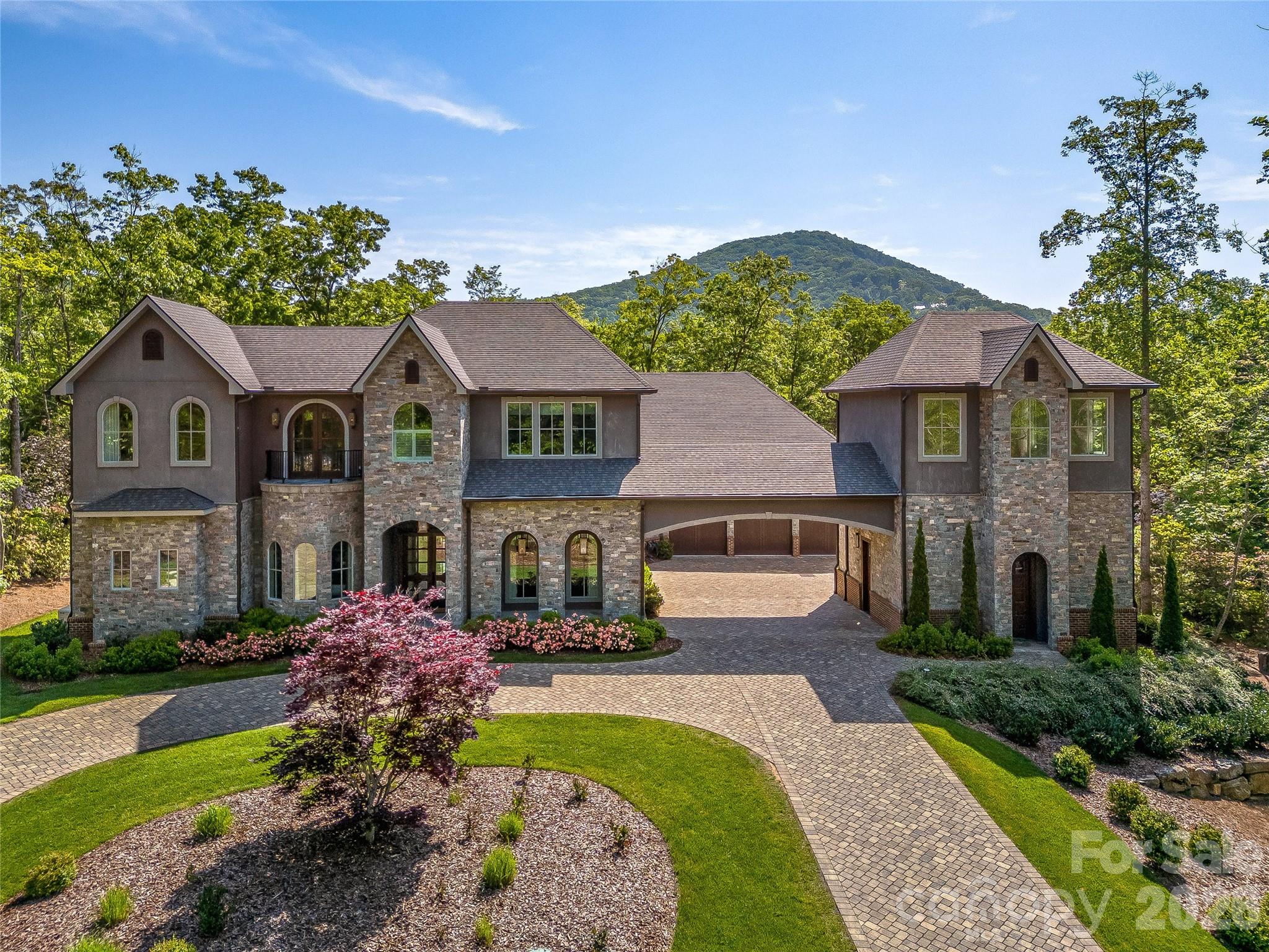 Experience luxury mountain living at its finest in The Cliffs at Walnut Cove, Asheville’s premier private golf and wellness community. Perfectly positioned within half a mile of The Golf House & Tavern, this extraordinary modern estate blends sophisticated design, master craftsmanship, and timeless elegance. Completed in 2019, 1905 White Tree Trail rests gracefully on a beautifully landscaped 1.24-acre corner lot surrounded by natural beauty and mountain serenity.
A grand entry welcomes you with four-point gas lanterns, setting the tone for the level of detail and design found throughout. Boasting more than 6,000 square feet of thoughtfully designed living space, this custom-built residence seamlessly combines contemporary architecture with warm, natural materials. The open concept layout connects the living, dining, and kitchen areas, creating an ideal setting for both entertaining and everyday living.

At the heart of the home, the Great Room makes a dramatic statement with soaring 25-foot ceilings, a breathtaking floor to ceiling wall of windows, and a stunning 72-inch crystal chandelier that anchors the space. A see through fireplace elegantly connects the Great Room, dining area, and office, offering both visual appeal and warmth.

The chef’s kitchen is a true showpiece, thoughtfully designed for both function and style. It features approximately 18 square feet of custom crafted black walnut butcher block seamlessly paired with 45 square feet of solid marble countertops, providing exceptional workspace. Premium appliances include a dual-fuel 60-inch Wolf range, ultra-low decibel hood vented to the exterior, and a WiFi-enabled Sub-Zero refrigerator and freezer designed to be panel-ready for a seamless custom cabinetry finish. Two separate sink basins enhance functionality, while an additional sink in the butler’s pantry makes entertaining effortless.

The main-level primary suite offers a private retreat, complete with a fireplace and a stunning sunrise window featuring remote controlled, motorized window treatments with integrated blackout shades. The spa-inspired primary bath includes radiant heated floors, a slipper tub, glass-enclosed shower, and custom backlit dual closets. Radiant floor heating extends to the home’s guest bathrooms, adding comfort and luxury throughout. A main-level guest suite provides privacy and a beautifully appointed en suite bath.

Upstairs, a bright sitting area overlooks the Great Room, accompanied by two additional bedrooms and a full bath with double vanities. A spacious bonus room and dedicated media room provide flexible living and entertainment options. The distinctive two-story tower offers exceptional versatility and could be customized as a private gym, golf simulator, guest quarters, or creative studio.

Designed with both practicality and luxury in mind, the three-car garage features tall ceilings and is car-lift ready, offering the potential for expanded vehicle storage. The expansive 1.24-acre lot provides ample space for outdoor living, whether enjoying the natural surroundings as-is or creating a future outdoor oasis.

Residents of The Cliffs at Walnut Cove enjoy access to world class amenities, including a Jack Nicklaus Signature golf course, state-of-the-art wellness center, indoor and outdoor pools, tennis and pickleball courts, and miles of scenic hiking trails. Membership opportunities extend access to all seven Cliffs communities, delivering an unmatched lifestyle experience.

Located less than eight miles from the Asheville Regional Airport and just minutes from downtown Asheville, this exceptional property offers the perfect balance of luxury, privacy, and convenience.

Experience refined living, architectural excellence, and the beauty of Western North Carolina at 1905 White Tree Trail, a home where modern design meets mountain serenity.

Book your showing today!