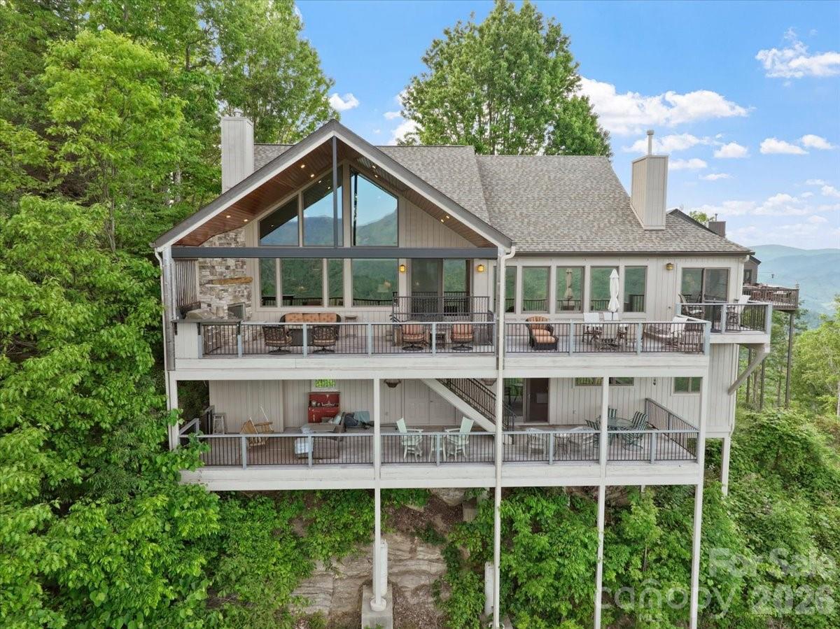 You will be amazed at the STUNNING PANORAMIC MOUNTAIN VIEWS from this exquisite 4 BR/5BA single-family home in the Boulder Pass community at MOUNTAIN AIR, blending luxury and mountain charm. This house was remodeled in 2008, taking it from just under 2200 sf to over 4,000 sf, with more than 1,400 sf of outdoor view deck space. Situated on a corner, this home has an incredible, long-range mountain panorama of more than 200°, as well as breathtaking sunrise views, and access to the sunset from the front porch. There are two covered decks of Brazilian Ipe Hardwood on the eastern-facing view side, plus the western-facing front porch, for relaxing and entertaining. Custom, local-artisan details create a truly one-of-a-kind living experience. An illuminated stained-glass mural greets you at the front entry, while character-rich floors of mixed hardwoods including Poplar, Oak, Walnut, and Wormy Chestnut flow through the main living areas. The dining room features a hand-crafted Wormy Chestnut dining table with a Walnut inlay runner, customized to seat 10 comfortably. The soaring ceiling in the great room opens to a versatile loft with an office area. The walk-in butler's pantry holds a second refrigerator/freezer, convenient to the open kitchen at the dining room, with granite counters and stainless appliances, including a new convection microwave over the gas range. The great room bar has plentiful cabinetry, with a wine cooler. The main level includes an updated ensuite bath with glass-enclosed shower, soaking tub with jets, and heated tile floors. There are 3 fireplaces, one with a remote starter, including a fireplace on the upper-level deck where you can enjoy panoramic views of the Black Mountain Range and Cane River Valley. This beautiful home is spectacular throughout, including an enviable lower level featuring a catering kitchen with pull-out refrigerated drawers, a drawer microwave, and a farmhouse sink, conveniently located steps away from the lower view deck for fabulous entertaining possibilities. There's also a breakfast nook, a den with a custom wine cooler, a heated tile floor, king bedroom, laundry, and two private baths, perfect for your guests. All appliances convey, including 2 refrigerators, washer and dryer. Most furniture/furnishings will convey, except the seller's personal exclusion list of personal items. Landscaping is taken care of for you, for a lock-and-leave experience.  This bespoke residence was masterfully designed to blend luxury and artistic craftsmanship for everyday functionality.