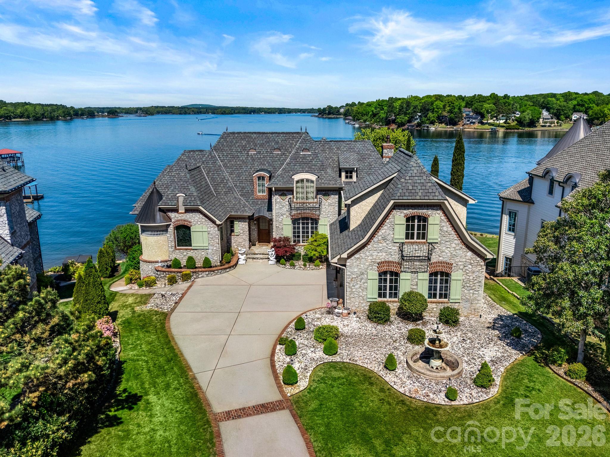 Exquisite French Country waterfront estate in the gated community of Joslin Pointe, offering panoramic main channel views of Lake Wylie, refined architecture, and an exceptional outdoor living experience. Perfectly positioned along the shoreline, this custom home blends timeless European design with over 7,000 square feet of thoughtfully designed living space. From the moment you arrive, the home’s stone exterior, manicured grounds, and architectural presence set the tone, while expansive water views create a breathtaking backdrop throughout.
The main level features a spacious primary suite and elegant living areas filled with natural light, designed for both everyday living and effortless entertaining. The gourmet kitchen features a Viking range and high-end appliances, and opens seamlessly to the main living spaces and outdoor terraces, creating a natural flow for gathering while taking in the views. Upstairs offers generously sized bedrooms with more views, while the finished walk-out basement is designed for elevated entertaining and everyday enjoyment. This level features a full bar, expansive living areas and flex spaces, and beautifully finished acid-stained concrete floors with a rich, marbled appearance, adding warmth and character to the space.
Outdoor living is where this home truly shines. A series of beautifully designed terraces lead to the water, featuring a fire pit, pergola, and multiple seating areas that create a private, resort-style setting. The newly installed WaterJack dock (2026) offers immediate access to Lake Wylie, making it easy to enjoy boating, sunsets, and lake life at its best.
Additional highlights include a large walk-in attic, multiple storage areas throughout, and a seamless whole-home audio system, offering both convenience and thoughtful functionality.
Located within Joslin Pointe, one of the area’s most exclusive gated waterfront communities, this home is part of a limited collection of just forty residences, including only thirty waterfront homes. Known for its French country architecture and old-world charm, the community features gas lanterns, elegant fountains, manicured landscaping, and a true sense of privacy, all set along the shores of Lake Wylie. It is the only gated waterfront community on Lake Wylie located in Rock Hill, offering a rare combination of exclusivity, character, and location just minutes from everyday conveniences.
A rare opportunity to own a high-end waterfront estate where panoramic views, exceptional design, and luxury living come together.