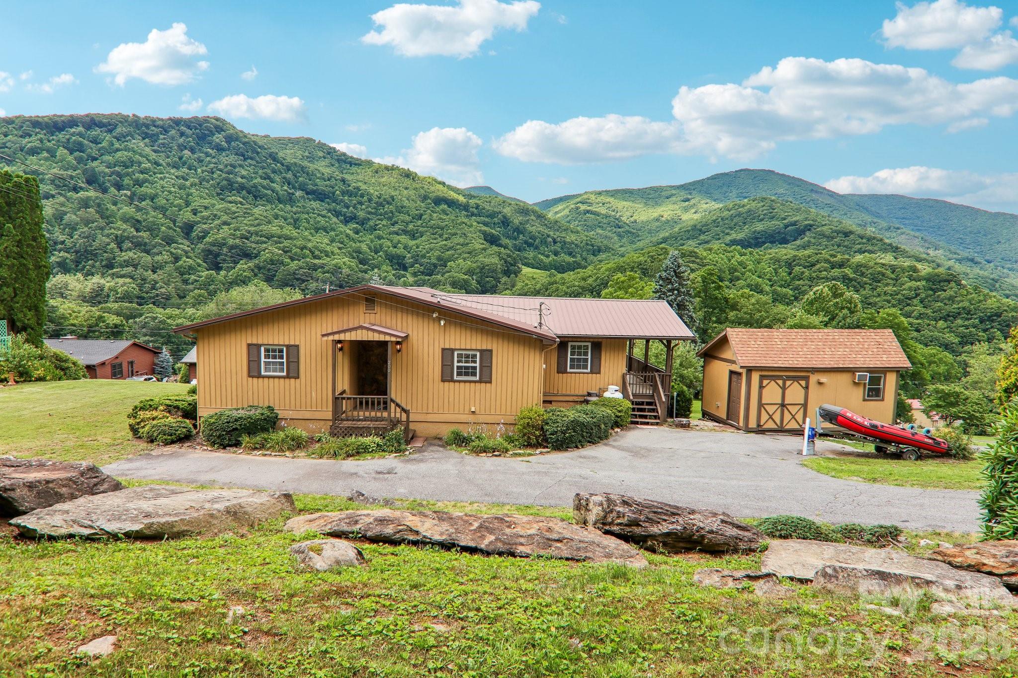 WELCOME HOME to 200 Holley Lane is a well-maintained mountain cabin in Maggie Valley, North Carolina, offering approximately 1,412 square feet of living space on a 0.38-acre lot. Built in 1985, the home features two bedrooms, a bonus room suitable for an office or additional sleeping area, and three full bathrooms. The open living area is anchored by a rustic stone fireplace with gas logs, creating a warm and inviting atmosphere.  

Don’t miss the Picturesque panoramic views of valleys and mountains, a durable metal roof, and high-speed internet service. Outdoor amenities include a wrap-around deck with mountain views, frequent elk sightings, and a detached workshop with electricity and water. Easy year-round access and proximity to Maggie Valley’s attractions make the property appealing as both a full-time residence and a vacation rental with strong income potential.