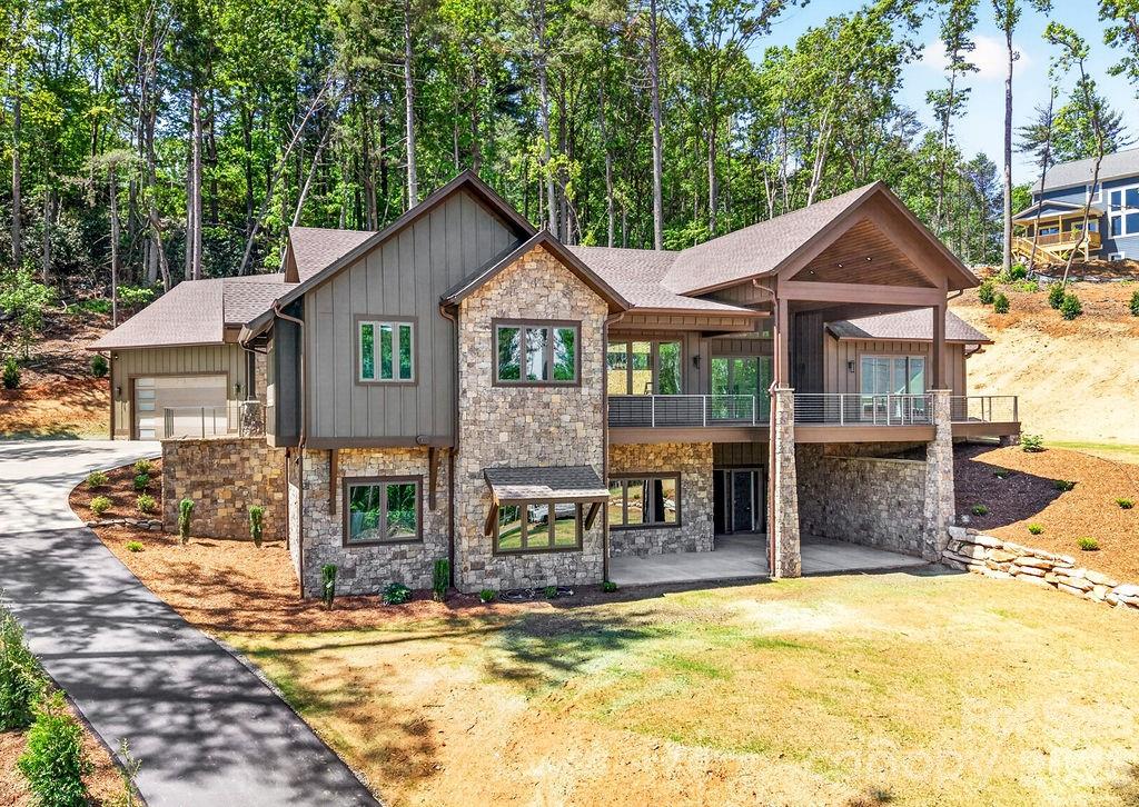 Perched on over an acre of beautifully landscaped Blue Ridge mountain land in the exclusive Northview neighborhood, this NEW mountain-modern masterpiece blends dramatic architecture with refined livability. Thoughtful design maximizes natural light and views with soaring ceiling heights, expansive windows, and premium finishes throughout.

From the moment you arrive, the cut stone exterior entrance and flagstone porch create a striking first impression, complemented by durable LP Smart siding engineered for anti-fade, anti-mold and anti-microbial performance. Built with 2x6 framing, spray foam insulation, a poured concrete foundation reinforced with rebar, an extensive drainage and waterproofing system, 2 HVAC systems, On-demand natural gas water heater, Anderson casement windows, and a whole house Generator, this home was constructed for longevity and peace of mind.
Inside, 10 foot ceilings and 8 foot solid wood doors create an airy, upscale ambiance.  The 3/4 inch solid white oak flooring flows beautifully throughout the main living areas, accented by substantial three piece base molding and custom soft close dovetail cabinetry.

The open, chef’s kitchen is equipped for culinary personalities: quartzite countertops, a spacious island, huge walk-in pantry, 48 inch natural gas range, and premium THOR stainless appliances that flow into generous living and dining areas — perfect for entertaining or relaxed mountain living. Three bedrooms and 2.5 baths on the main level provide single-floor convenience, with a total of five bedrooms and 3.5 baths across the home. 

The Primary suite is a retreat highlighted by a private Trex deck, dual custom finished walk-in closets, linen closet, separate toilet room, Spa inspired bath with Bahia Quartzite and a huge shower with dual shower heads and a waterfall feature.

The heated walkout basement expands your living space with 12 foot ceilings, a special living area with TV box, wet bar with sink and mini-fridge plus a dedicated wine/safe room.

Outdoor living is extraordinary: over 1,500 square feet of Trex decking and concrete patios feature sleek stainless cable railings and multiple entertaining zones. Ample storage on both the main and lower levels keeps the interior uncluttered, while rich exterior stonework anchors the home in its natural setting.

Ideally located between Hendersonville and Asheville, this residence offers privacy, winter mountain vistas, and immediate access to the region’s dining, arts, and outdoor recreation — a modern sanctuary for those who seek luxury and authenticity in equal measure.

Location is less than 12 minutes to Asheville Regional Airport, breweries, grocery stores, world class healthcare, Mills River Park, and Interstate 26,