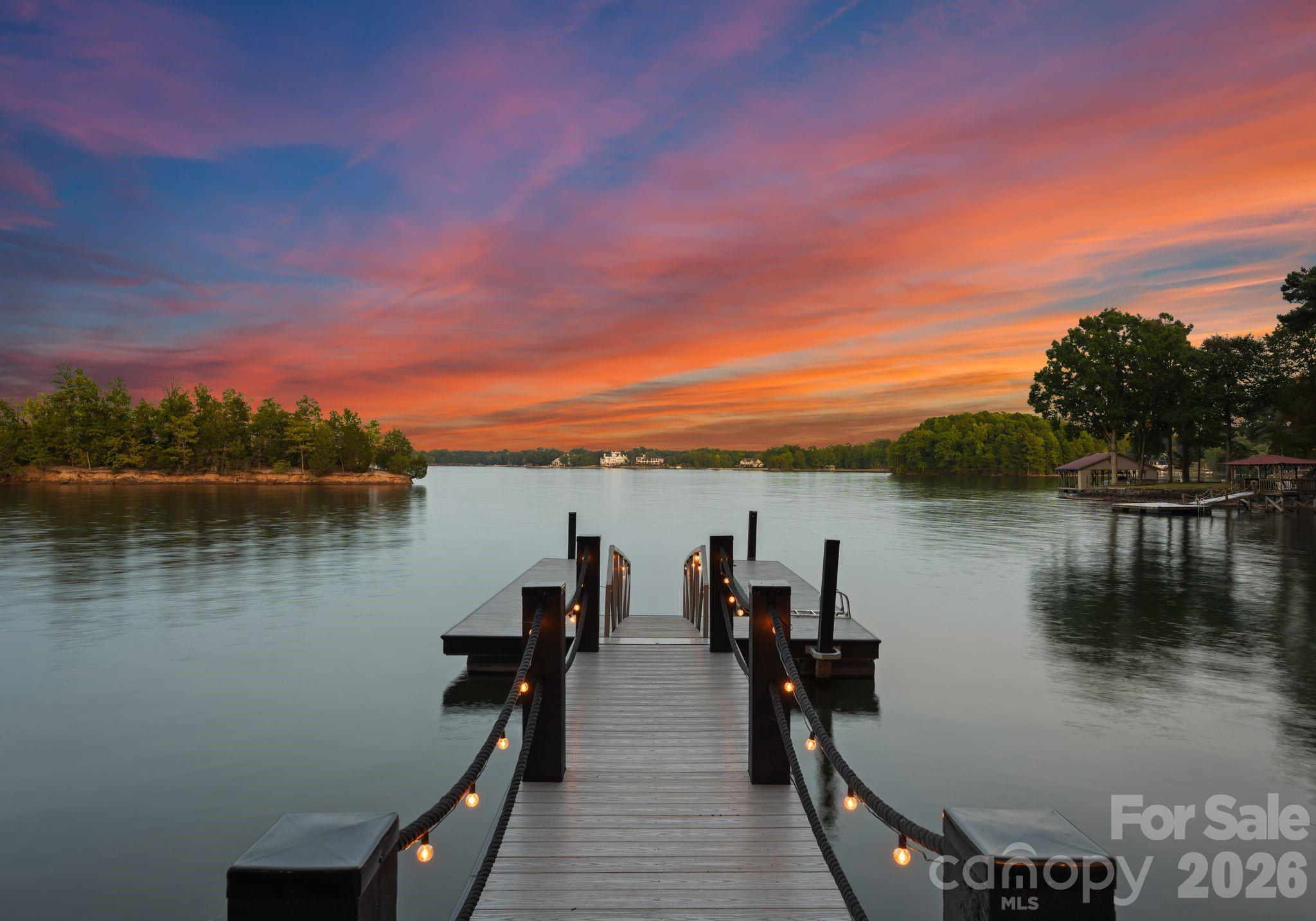 Waterfront living just beyond The Point on Lake Norman! This beautifully crafted home is tucked off the main channel near a charming island, offering calm water, sweeping sunrise views, and incredible long-range sunrise views. Enjoy your own private pier, rare sandy beach, and plenty of space to add a pool and spa.
Designed for comfortable main-level living and optimizing the views, the open-concept floor plan is filled with natural light.  Expansive sliding glass doors open to a large lakeside terrace, creating seamless indoor-outdoor flow — perfect for entertaining or relaxing while taking in the views.
Upstairs features spacious guest suites, while the fully finished lake level includes a movie room, wine cellar, and flexible space ideal for a home gym, office, or additional living area. This home exudes quality construction and architectural design and is a must see.
Outdoor living is a standout with three expansive terraces, a newly constructed dock with composite decking, and a low-maintenance Zen-style front garden. A detached two-car garage with storage above adds extra flexibility.
Located near The Point, with optional access to world-class amenities including championship golf, tennis, pickleball, dining, and more.
Septic permit is for 3 bedrooms; home offers potential for a 4-bedroom configuration.