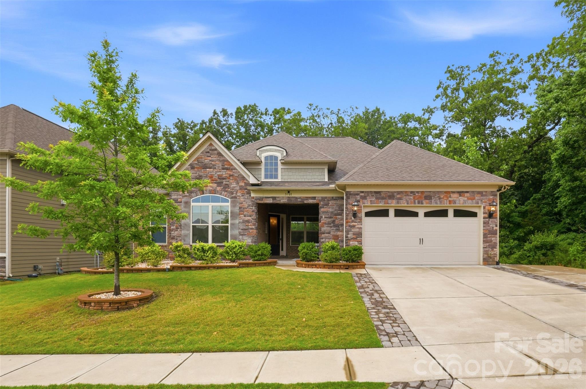 This well-designed floor plan offers spacious main-level living with 10-foot ceilings, an open layout, and a main-level primary suite featuring a sitting area and a custom-built walk-in closet. The gourmet kitchen is equipped with upgraded cabinetry, quartz countertops, stainless steel appliances, a gas cooktop, tile backsplash, a large island with seating, and a walk-in pantry with custom shelving—ideal for both everyday living and entertaining.

Two guest bedrooms are located in their own private wing on the main floor, each with custom walk-in closets and a shared bath nearby. A beautifully finished powder room with designer wallpaper is conveniently located in the main living area for guests.

The home also includes a private office with French doors, a formal dining room currently used as an additional sitting room, a planning center or “mom cave,” and a drop zone with custom cabinetry. The spacious laundry room offers abundant cabinetry, generous folding space, and a utility sink—features not often found together. Hardwood floors run throughout the main living areas, with tile in all baths and the laundry room.

The primary bath includes dual vanities, a soaking tub, and a large walk-in shower with bench seating. Upstairs, a loft area and a private en-suite bedroom provide the perfect setup for guests or additional living space.

Outdoor living is just as inviting, with covered and extended patios overlooking a private wooded backyard. The owners also invested in a large retaining wall to create a more functional, flat yard space, and a gas line has already been added for easy grill setup. And the garage? Epoxy flooring and a Level 2 EV charger for your electric car!