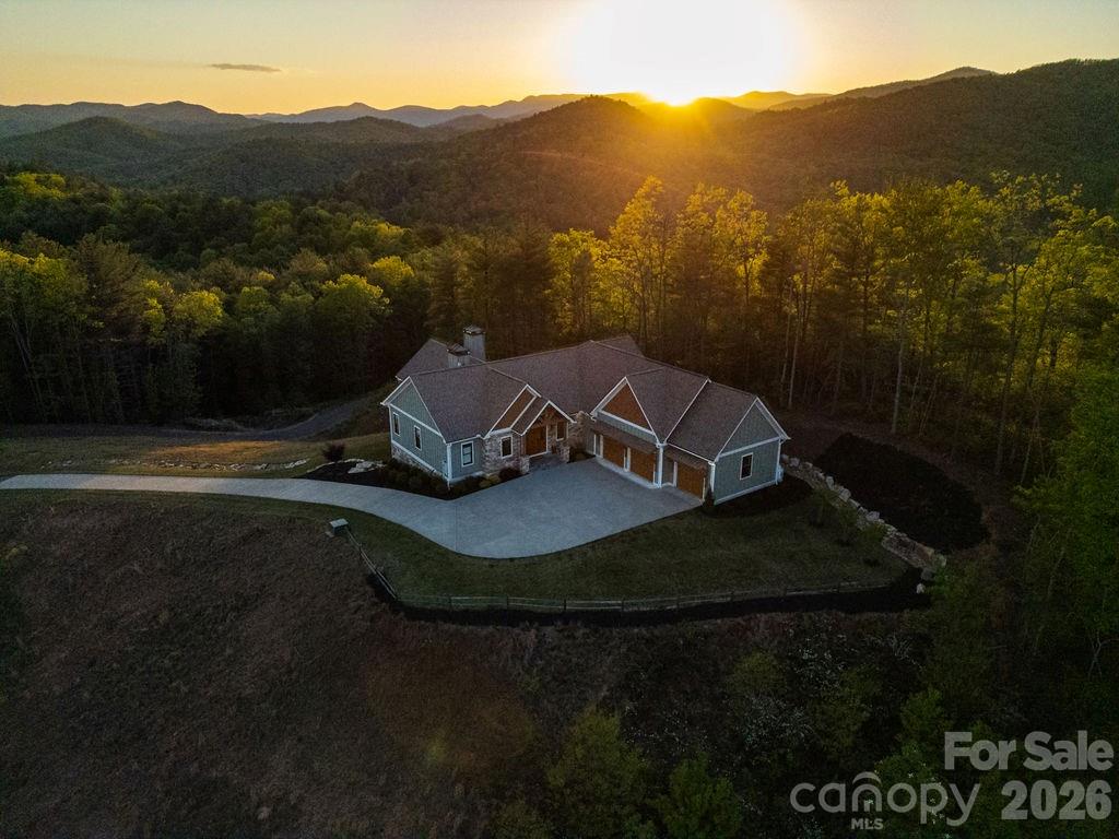 “A true Western North Carolina legacy property—120.94 acres of protected beauty featuring springs, a waterfall, abundant wildlife, and sweeping views, centered around a one-of-a-kind custom home designed to stand the test of time. Properties of this scale, privacy, and craftsmanship are rarely offered.”
Accessed through a private electric gate, a gently sloping 3/4 of a mile paved drive winds through mature timber, gradually rising approximately 300 feet to the homesite atop Little Mountain. The land itself is both usable and thoughtfully improved, featuring a small creek, natural springs, and an established one-mile, 8-foot-wide loop trail—ideal for hiking or UTV access—providing easy enjoyment of nearly the entire property. A large equipment shed offers convenient storage, and the property benefits from a timber tax exemption. Surveyed in fall 2025, the acreage reflects careful stewardship and long-term vision.
Completed in 2023, the custom-built residence is perfectly positioned to capture what may be some of the finest views in the area, overlooking the surrounding mountains and the French Broad River Valley. Offering approximately 3,847 square feet of heated living space, the home is complemented by thoughtfully designed outdoor living areas, including a 400-square-foot screened porch with vaulted ceilings, fireplace, and TV, a 400-square-foot covered patio with an additional fireplace, and a 170-square-foot open grilling deck—all designed to take full advantage of the property’s natural setting and year-round climate.
Inside, the home reflects quality and intention throughout, with high-end finishes and features including Sub-Zero appliances, gas cooktop, walk-in pantry, dual fuel oven, horizontal gas fireplace, 2 bedrooms with 2 full baths and 1 half bath on the main level, and 2 bedrooms with full baths on the lower level. You will love the spacious attached 3 car garage. It also has a Generac whole-home propane generator. Extensive boulder hardscaping and professional landscaping further enhance the setting while maintaining a natural, mountain aesthetic. An additional 700 square feet of basement space provides flexibility for storage or future use.
Despite its size and privacy, the property is remarkably accessible—located just 2.4 miles from Pisgah National Forest, 5.7 miles from downtown Brevard, 13.5 miles from Asheville Regional Airport, and within easy reach of DuPont State Recreational Forest, Hendersonville, and Gorges State Park.
Whether enjoying the consistent mountain breeze from the porch, gathering around one of the outdoor fireplaces, or exploring the trail system with friends, this property offers a rare combination of scale, comfort, and livability. A truly exceptional opportunity to own one of the area’s most distinctive and private estates.
