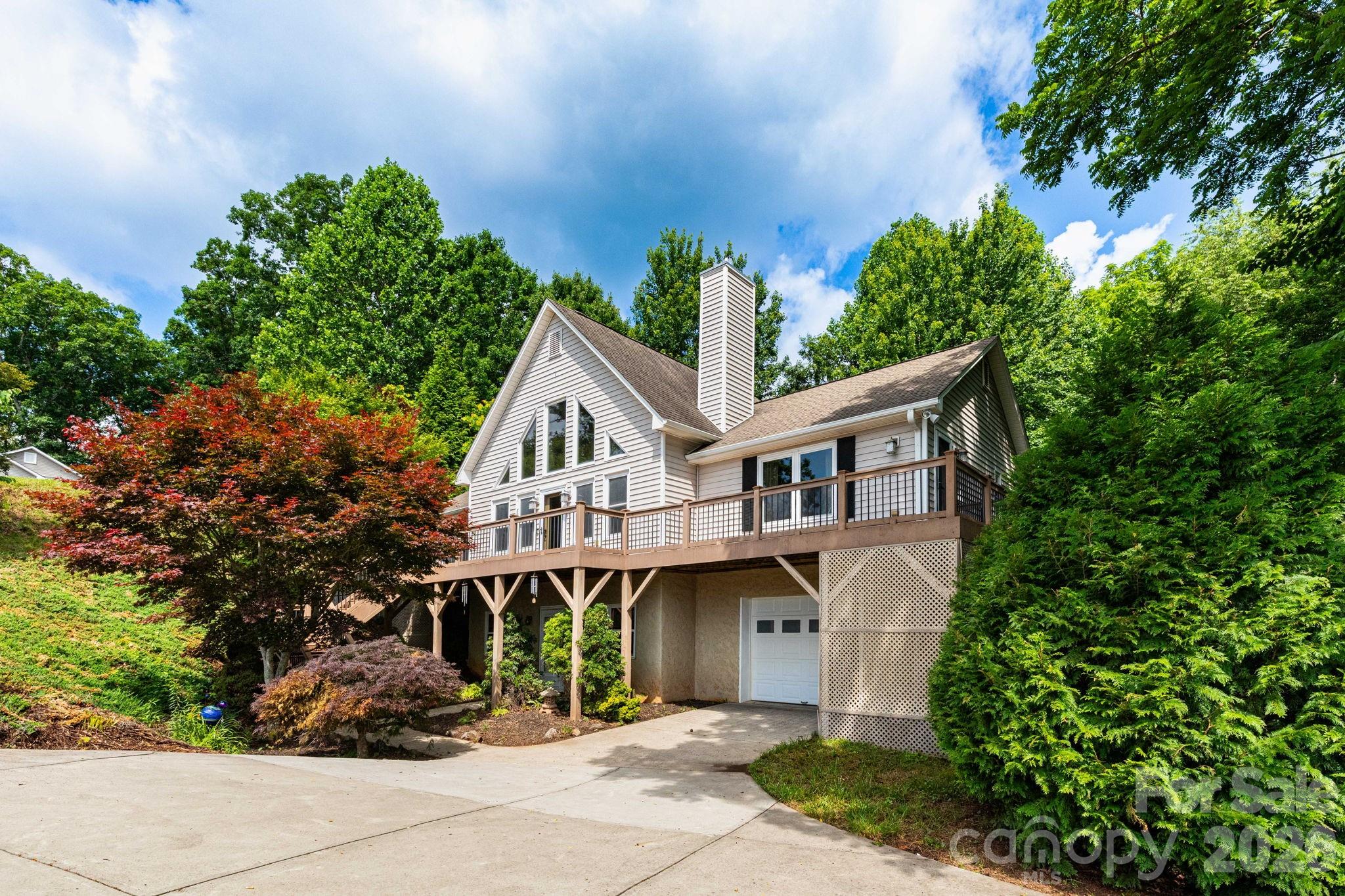Clean mountain lines and expansive views define this inviting Candler home, ideally situated on a quiet cul-de-sac just 10 minutes to I-40, shopping, and dining, and only 20 minutes to downtown Asheville. The main level features a bright, open floorplan anchored by a striking A-frame wall of windows that captures beautiful long-range mountain views and fills the space with natural light. A stunning stone fireplace adds warmth and character to the living area, while the kitchen offers both style and function with a large island and breakfast bar, stainless steel appliances, and granite countertops. Hardwood floors run throughout the main living spaces, enhancing the home’s cohesive feel.

Three bedrooms and two bathrooms are conveniently located on the main level, offering comfortable everyday living with a thoughtful layout. The spacious primary suite serves as a private retreat, featuring a large ensuite bathroom with a soaking tub, separate shower, water closet, and dual walk-in closets outfitted with custom shelving for exceptional organization. The two additional bedrooms are generously sized and also include walk-in closets with custom shelving, providing ample storage for family members or guests. A well-appointed hall bathroom serves these bedrooms and guests alike.

The finished basement significantly expands the home's living space and versatility, featuring a large family room complete with a wet bar/kitchenette—perfect for entertaining, hosting game days, or accommodating extended guests. A bonus room offers flexibility for a home office, fitness room, hobby space, or guest accommodations, while a full bathroom adds convenience. The oversized laundry room provides abundant storage and workspace, making it easy to keep household essentials organized.

Outdoor spaces shine with a peaceful screened porch and a wraparound sun deck designed to take full advantage of the sweeping mountain views. The .83-acre lot includes a spacious, shaded backyard with plenty of green space to relax or play. This property offers the perfect blend of comfort, versatility, and scenic mountain living.