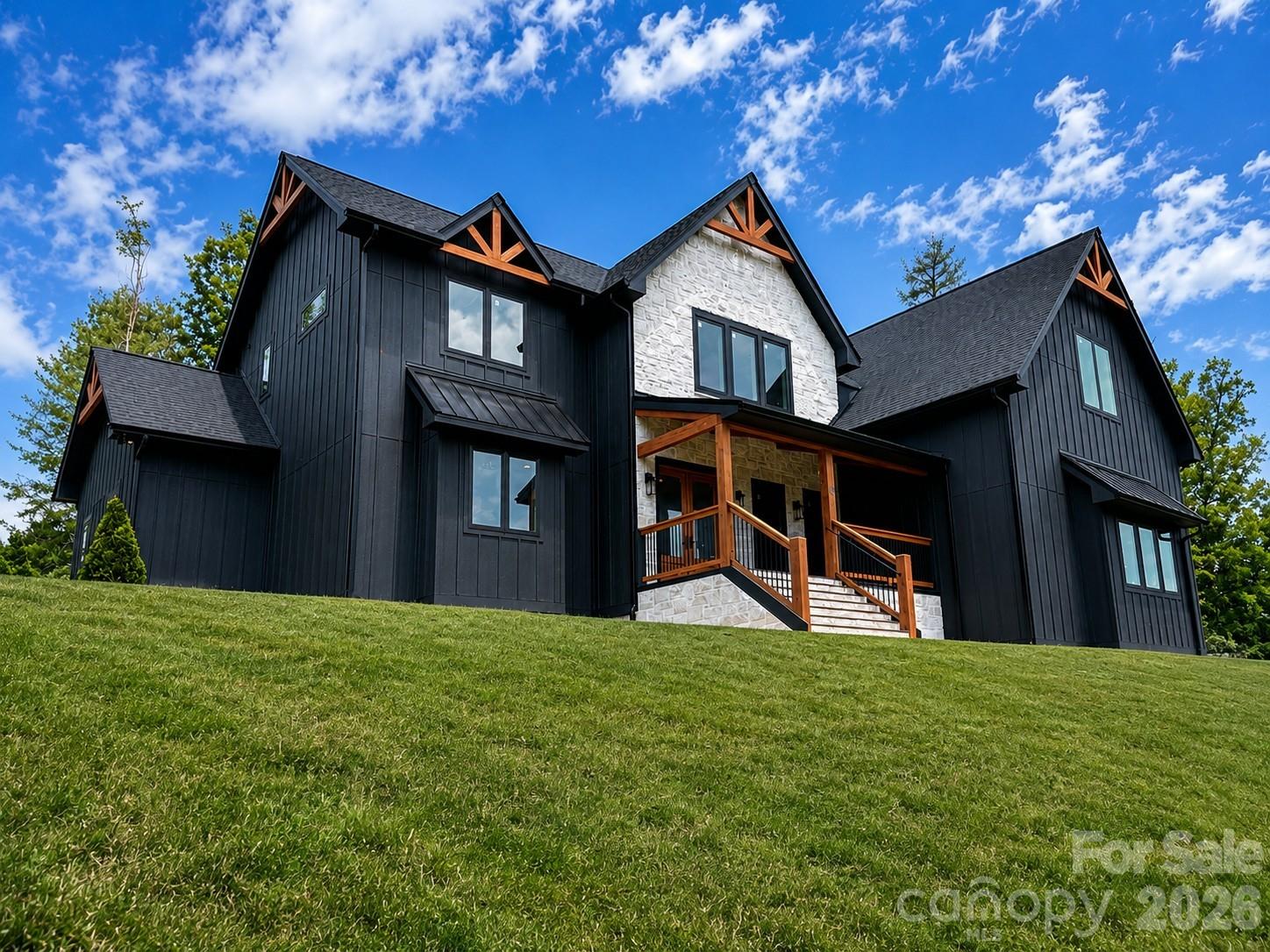 SIGNIFICANT BUYER INCENTIVE — Additional Detached 2-Car Garage Included at Current List Price

This  exceptional craftsman-inspired luxury mountain home now includes a detached 2-car garage/workshop at no additional cost. Combined with the attached 3-car tandem garage, the property will offer approximately 1,540 square feet of garage space with capacity for up to five vehicles—an extraordinary feature rarely found in luxury mountain homes at this price point.

Built by a respected local builder responsible for more than a dozen homes within Garrison Hills, this thoughtfully designed residence is situated on an elevated 1.06-acre homesite that captures long-range mountain ambiance while also providing rare flat backyard and side-yard spaces for outdoor activities.  Conveniently located just minutes from downtown Weaverville, approximately 15 minutes from downtown Asheville, and with easy access to I-26, the home offers the ideal combination of privacy, accessibility, and luxury living.

The home welcomes you with an open foyer, a dedicated main-level office with glass doors, and a dramatic great room featuring soaring 20-foot vaulted ceilings, oversized windows, and a stunning floor-to-ceiling stone fireplace. Ten-foot ceilings throughout the main level and custom 8-foot doors create an impressive sense of scale while maintaining warmth and livability.

Expansive sliding doors open to a screened rear porch with a wood-burning fireplace, creating a seamless indoor-outdoor living experience ideal for entertaining or quiet mountain evenings. The chef's kitchen combines elegance and functionality with rich gray wood-tone cabinetry, quartzite countertops, Thermador appliances, premium finishes, and a well-appointed butler's pantry.

The main-level primary suite serves as a private retreat, offering direct access to a screened porch, dual walk-in closets, and a spa-inspired bath featuring a freestanding soaking tub and an oversized walk-in shower clad in dramatic polished porcelain tile.

Upstairs, a spacious sunlit loft overlooks the great room and provides the perfect setting for a reading area, secondary office, or flexible living space. A large bonus room and two generously sized ensuite bedrooms offer comfort, privacy, and versatility for family and guests.

Offering nearly 4,000 heated square feet, multiple outdoor living areas, exceptional garage capacity, and the quality craftsmanship that has made this builder a trusted name within Garrison Hills, this property presents a rare opportunity to enjoy luxury mountain living in one of North Buncombe County's most desirable communities.