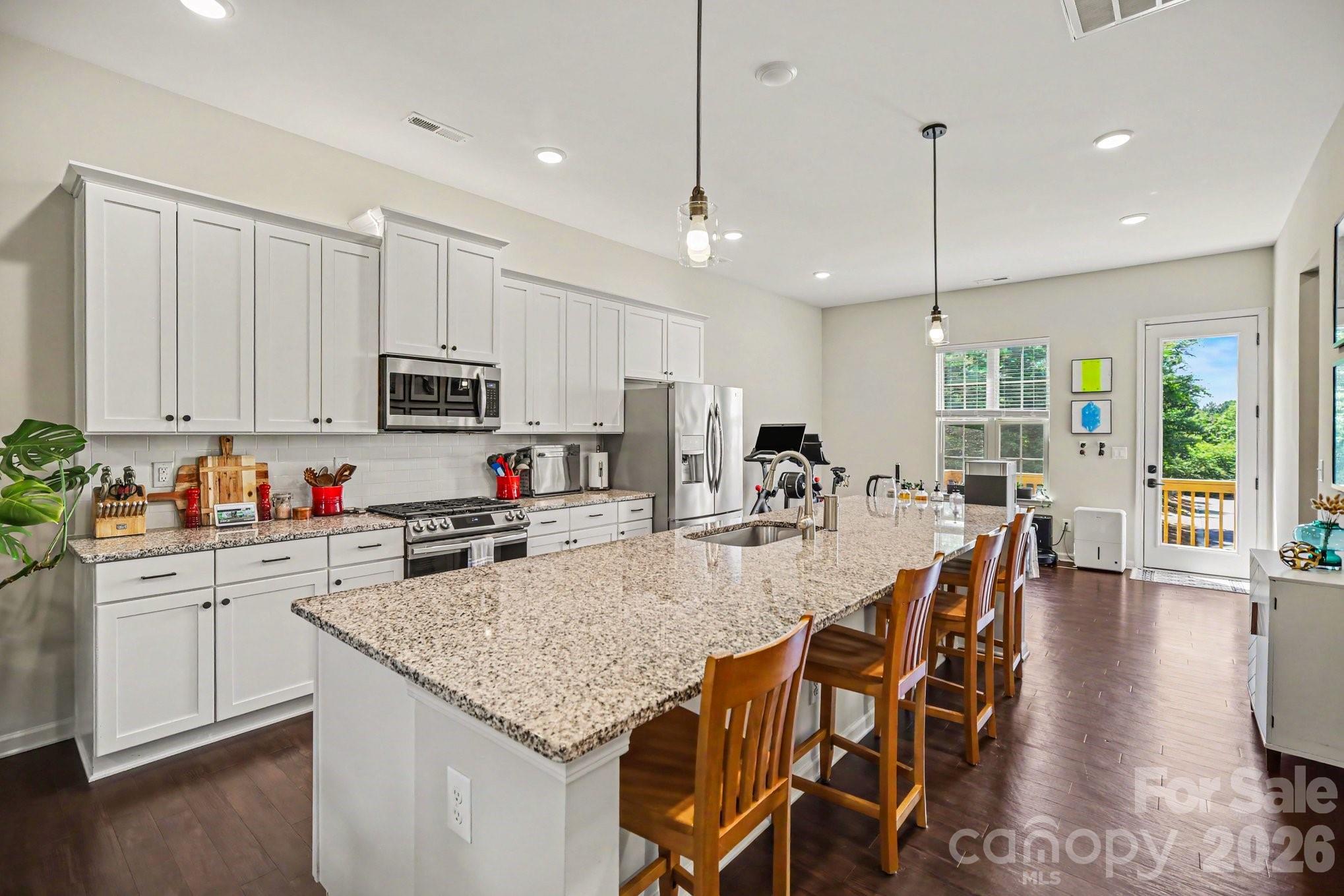 Among the most thoughtfully upgraded townhomes in the community, this three-story home goes well beyond the standard build—a coveted center-kitchen layout, a fully renovated primary bath, a complete smart-home system, and a finished, move-in-ready garage, all just steps away to the Arrowood Light Rail Station (Blue Line).
Just inside, the flexible first-floor room is offered as an optional bedroom, with an opening already sized for a door to make it a private bedroom—and just as easily an office, gym, media room, or playroom, with a half bath and generous storage close by.

The main living level is built for gathering. As one of only a select few floor plans in the neighborhood with the sought-after center-kitchen layout, it centers on a standout island stretching more than 12 feet—a scale you rarely find even in much larger single-family homes. Farmhouse pendants hang above it; matte black hardware runs throughout the cabinetry. The kitchen is dialed in for both cooking and hosting, with an upgraded Samsung appliance package, a Frigidaire Gallery French-door refrigerator, a deep single-basin sink with a touchless Moen faucet and InSinkErator disposal, a pull-out trash cabinet, and a large walk-in pantry. The open layout flows from kitchen to dining to living room and out to the balcony.

Out back is something most homes here don't have: this is one of only a handful of homesites in the community that backs to trees rather than neighboring units, giving the deck real privacy. It still overlooks the community pool and cabana, but from a comfortable distance—close enough to enjoy, far enough to stay quiet.

Upstairs, the primary suite is a true retreat, with tray ceilings and custom barn doors at the closet. Its fully renovated bath is the highlight of the home—a premium tile shower behind a frameless glass enclosure, an upgraded dual-sink vanity with matching mirrors, and wood-look tile flooring, all properly waterproofed with a Schluter system so it's built to last. Two more bedrooms and a full bath complete the floor, and the laundry sits right where you need it—on the bedroom level, with a Maytag washer and dryer included.

The smart-home setup is complete and already installed—no starter kit to build on. Each of the three floors has its own smart thermostat and sensor, so every level stays comfortable independently. Keyless smart locks secure the front and garage doors, a video doorbell covers the entry, an outdoor camera with floodlight watches the exterior, and smart smoke-and-carbon-monoxide detectors are installed throughout. Smart light switches handle the main living areas. It's all name-brand Nest and TP-Link gear, working together from day one.

The garage got the full treatment, too—a professionally applied epoxy floor, fresh paint throughout, a quiet wall-mounted smart opener that frees up the ceiling, and a wall of custom shelving plus overhead racks for the kind of storage townhomes rarely offer. Matte black handles and hinges carry the finish details all the way through. Garage has a dedicated circuit for an EV Charger.

Community amenities include a pool, cabana, lawn maintenance, trash, and recycling. The location is hard to beat—minutes from I-77, South End, Uptown Charlotte, Charlotte Douglas International Airport, and plenty of shopping, dining, and entertainment.

Here's the best part: most homes leave the next owner with a to-do list. This one hands you the keys. From the renovated primary bath to the extensive smart-home tech, finished garage, and custom storage, the work is already done. This is a true move-in-ready home, ready to be enjoyed from day one.