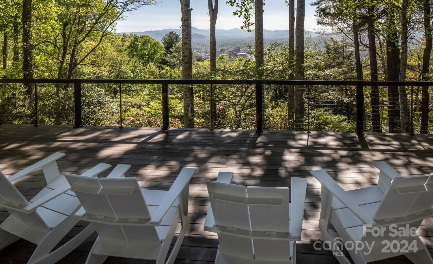 This stunning, extensively renovated home offers year-round views of downtown Asheville's skyline, surrounding mountains, and spectacular sunsets on Town Mountain. Located only a 10-minute drive from several country clubs, this property features four spacious bedrooms, a flex room for office or exercise space, and four and a half completely updated bathrooms. The gourmet kitchen, equipped with high-end appliances and finishes, is perfect for culinary enthusiasts. The cozy family room and reading lounge are ideal for relaxing, while the expansive living room offers endless entertaining possibilities. Additional amenities include a three-car garage, two primary suites—one on each level—and ample storage. Outside, the home sits on a generous 1.5-acre lot with a flat, fenced side yard, a charming terrace, and a deck with panoramic views, providing a perfect blend of privacy and open space. This 'like new' home offers luxurious living in one of Asheville's most sought-after locations.