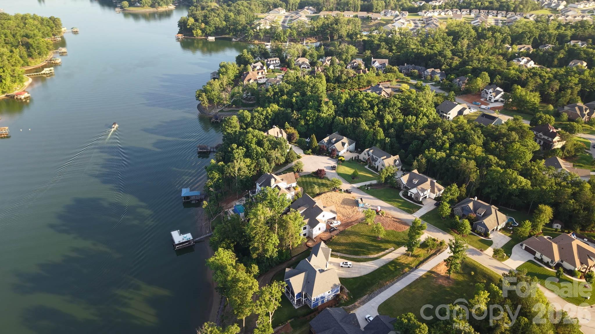This beautiful new home is constructed on one of the last waterfront dockable custom lots in the established lake front community, Handsmill on Lake Wylie. The main level features a spectacular open kitchen with wet bar, dining area, great room with a 60" linear gas fireplace, keeping room, guest bedroom or study with ensuite bath, powder room, drop zone, laundry room, walk-in pantry and large covered deck with outdoor gas fireplace and unbelievable views of Lake Wylie. The second floor features two secondary bedrooms with ensuite baths and a large bonus room.  The basement level is perfect for lake life entertaining or very comfortable multi-generational living. It features a second primary bedroom suite, kitchen, dining area, utility room with laundry, workout or media room, large living room, and best of all a bar room with glass roll-up doors overlooking Lake Wylie.  Bar is fully functional and ready for this upcoming football season with bottle shelves, a sink, beverage refrigerator and icemaker. The rear yard features a winding path through beautiful old Oak trees to a covered deep-water dock and beach area.  Plenty of space in the backyard to add a pool and the electrical system has been upgraded so you have enough power for all your future needs; pool, spa, sauna, shore power, dock lift...you're covered. The home is also completely pre-wired for all your networking, speaker, and security needs. Handsmill is one of Lake Wylie's premier gated custom home communities, featuring a quiet atmosphere, a community pool, clubhouse with workout facilities, boat storage and just minutes from top rated Clover schools, restaurants, and shopping. The home will be complete and ready for move in fall 2026!