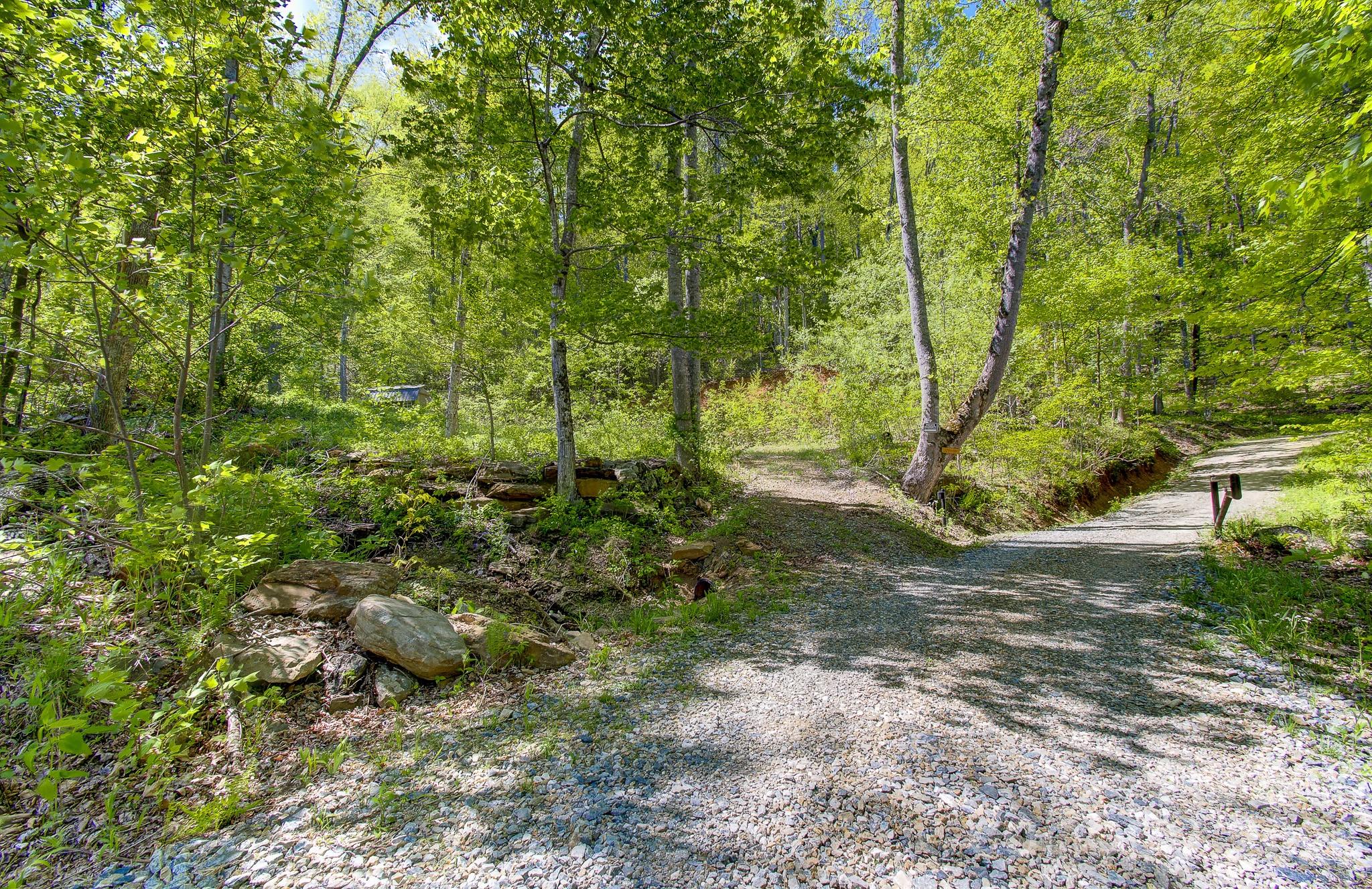 Tucked into the mountains of Candler, this 13.47-acre property offers a setting that’s increasingly hard to find—private, scenic, and anchored by a truly standout natural feature. At the heart of the property is a striking waterfall that feeds a stream below, creating a constant, calming presence that defines the land. Whether it’s the sound of the water or the view itself, this is the kind of feature you build a home around—imagine sitting on your back deck, overlooking your own waterfall as it flows just beyond. The property has already been prepared with two homesites in place, offering flexibility for a primary residence, guest home, or future investment. Positioned within an established neighborhood, you’ll enjoy a sense of community while still feeling completely tucked away in your own mountain retreat. With 13.47 acres to work with, there’s plenty of room to expand your vision—add trails that wind through the property and lead up to the ridgeline, where the potential for long-range mountain views awaits. Properties with this combination of usability, acreage, and such a defining natural feature are few and far between. *Pictures of homes on the property are for visualization purposes only of what could be built on the property. All plans will need to be approved and are subject to the neighborhoods covenants and restrictions*.
