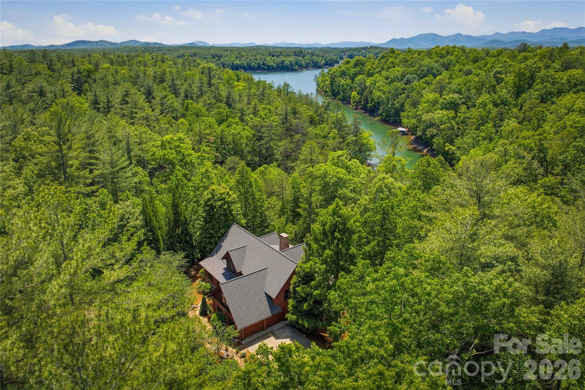You will feel yourself relaxing as you enter the winding drive to the ultimate private retreat offering rare waterfront seclusion set on nearly 3 wooded acres. Home is surrounded by mature landscaping with trails through rhododendron and laurel thickets and bounded on both sides by over 11 acres of community owned conservation area.This rare offering combines privacy, luxury and the ultimate waterfront lifestyle with room to breathe and space to play. Home features open floor plan perfect for large family gatherings or entertaining inside and outdoors. Could be multi-generational home with potential separate living quarters downstairs. As you enter you will find a spacious dining room. Living room with stone, woodburning fireplace with raised hearth and french doors opening to 12' x 34' screened porch with views of beautiful Lake James. Kitchen with breakfast area has newer Bosch stainless appliances, island with prep sink,5 burner cooktop, custom cabinetry and hood, walk in pantry laundry room with sink and cabinetry. Sunroom, that feels like being in a tree house, has french doors opening to screened porch. Enormous primary suite with lighted tray ceiling opens to ensuite bath with dual vanities, jetted tub, walk in tiled shower and huge primary closet. Upstairs features large bedroom with ensuite bath with tiled surround tub, bedroom #3, full bath and office (BR #4), large bonus room over garage, has no closet (potential BR 5) Walk out basement level has enormous family room with stone wood burning fireplace. wet bar,potential game room/billiard area, full kitchen with stainless appliances, wine room, pantry,safe room, huge storage room. Lower level opens to  12' x 34' covered patio. Additional sunroom/greenhouse/entertaining area  features tons of windows, stone walls with mini split, hot and cold water. Gentle walk or use path for ATV to covered dock with aluminum ramp, trex decking, hydro-hoist, kayak launch in deep clear water secluded cove. Plenty of room on dock to sit and enjoy your early morning coffee or afternoon glass of wine and enjoy serenity of the lake. Just a 3 minute boat ride or golf cart ride to Camp Lake James. Ownership in 1780 affords you membership to the Camp with amazing amenities  including community events, restaurant, fitness center, kids pool, Jr olympic sized pool, hot tub, pickleball and tennis courts, beach with lake toys, docks and outdoor lakeside bar. Home has attached oversized garage, Separate 25' x 37' garage for Rv/boat storage. 
New 30 yr roof 2024, main heat pump 2026, new hot water heater 2025, house painted 2022,new sump pump 2025. House has 4 BR septic permit. Bonus room over garage (BR#5) has no closet. Home conveys partially furnished. Duke Energy. Please take your clients to visit Camp Lake James!