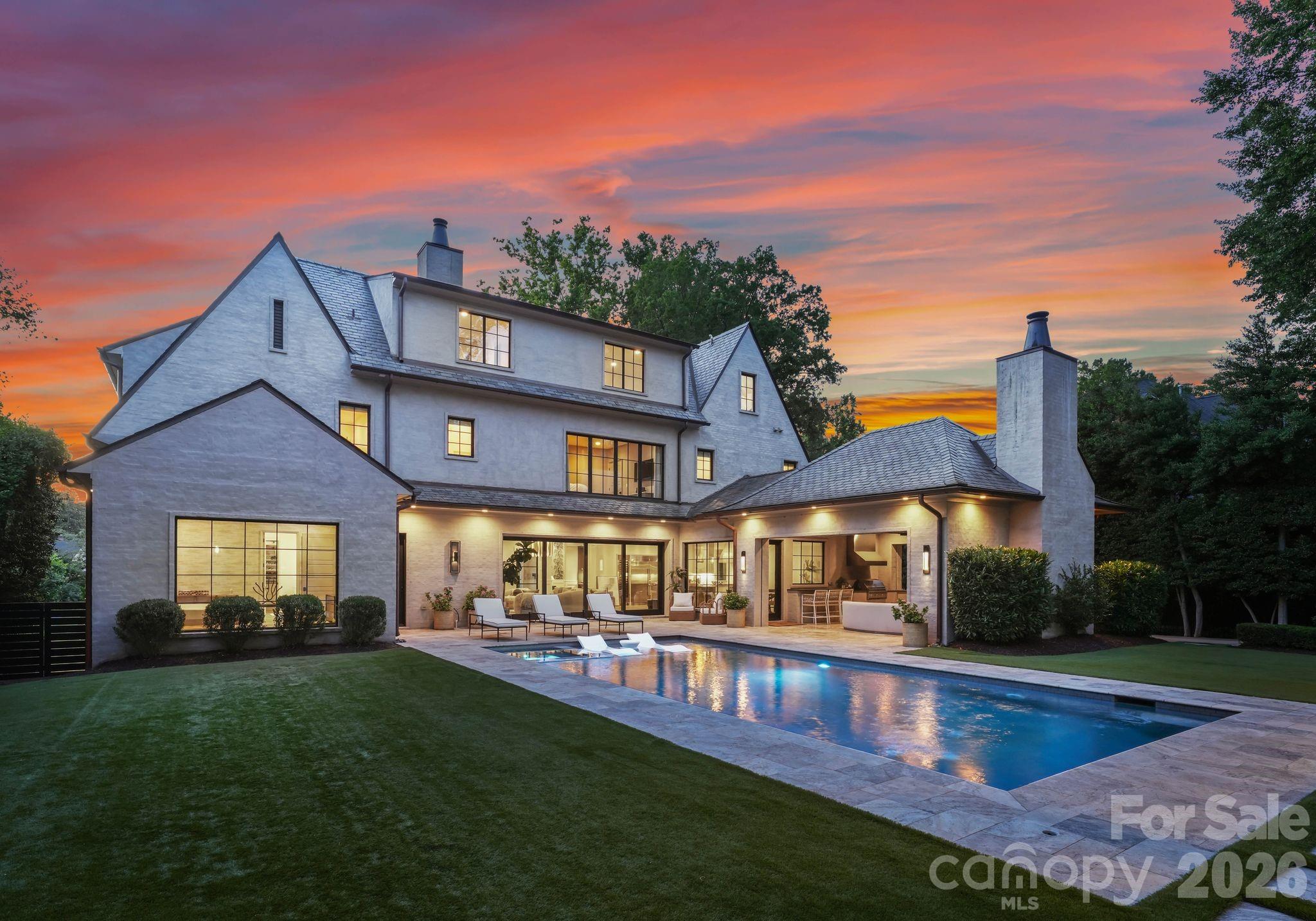 Set within one of Myers Park's most tranquil and private neighborhoods, this stunning custom estate sits on a spacious half-acre lot and delivers an exceptional standard of living across 7,374 square feet, plus a fully appointed guest house.

Arrive to a circular driveway and covered front entry, where a slate roof, slurry brick finish, and copper gutters offer a first glimpse of the craftsmanship within. Originally built as the personal residence of prominent Charlotte builder WK Phipps, every detail of this home reflects an uncompromising standard of quality.

Inside, abundant natural light fills an open-concept main level. A formal dining room features custom wainscoting and designer wallpaper. The living area is anchored by a gas fireplace, built-in bar with marble countertops, a beverage refrigerator, and automated slider doors opening to the backyard.

The chef's kitchen impresses with a professional-grade Wolf dual-fuel range, Sub-Zero refrigerator, freezer, and full-height wine refrigerator, a statement island, floor-to-ceiling custom cabinetry, and an oversized walk-in pantry.

The primary retreat on the main level is a true sanctuary. Expansive glass panel windows, custom wallpaper, motorized shades, motorized curtains, and a designer light fixture set a tranquil atmosphere. The spa-inspired bath features a floating double vanity with sconces, a private water closet, a freestanding soaking tub, and a walk-in glass shower with dual showerheads. The custom closet is equally impressive, with an island, built-in shelving, cabinetry, full-length mirror, and its own washer and dryer.

Upstairs, four guest bedrooms each feature ensuite bathrooms and walk-in closets alongside an oversized laundry room. The third level features a flexible bonus room with a powder room and multiple storage areas.

The backyard is a private resort. Automated slider doors open from the living room to a lush, fully fenced outdoor sanctuary featuring turf, stone pavers, a saltwater heated pool and spa with a tanning ledge, an outdoor shower, and a pool bathroom. The covered cabana is built for year-round entertaining, with a wood-burning fireplace, built-in grill, infrared heaters, a mounted TV, and automated shades and enclosure screens.

The detached four-car tandem garage offers a fully appointed upper-level guest suite complete with a wet bar, full bath, and space for a gym or office.

Control4 home integration, Sonos audio system, a generator, electric gate, and Tesla EV charger complete this one-of-a-kind offering. With proximity to top dining and retail in SouthPark, premier public and private schools, and an easy commute to Uptown Charlotte, this is Myers Park living at its absolute finest.